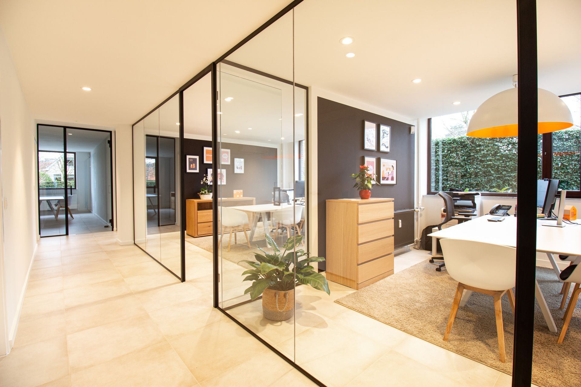 Moderne kantoorruimte met glazen wanden, witte bureaus en natuurlijk licht.