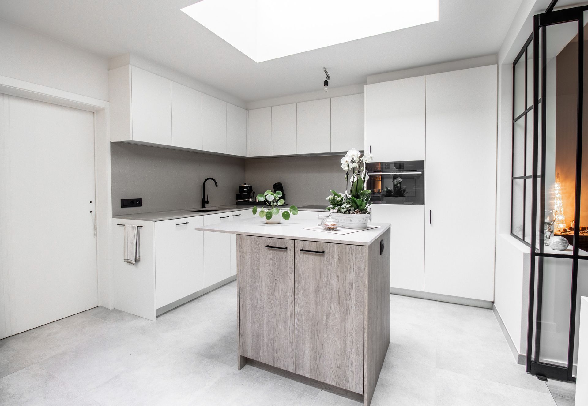 Moderne witte keuken met kookeiland en dakraam.