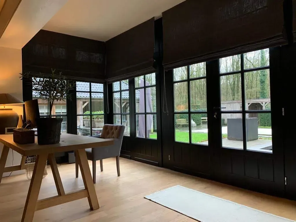 Kamer met donkere houten kozijnen, een bureau en uitzicht op een achtertuin.