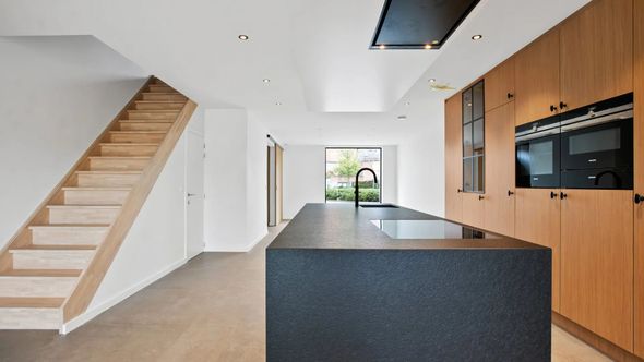 Wit huis met donker dak, grindpad, omgeven door bomen.