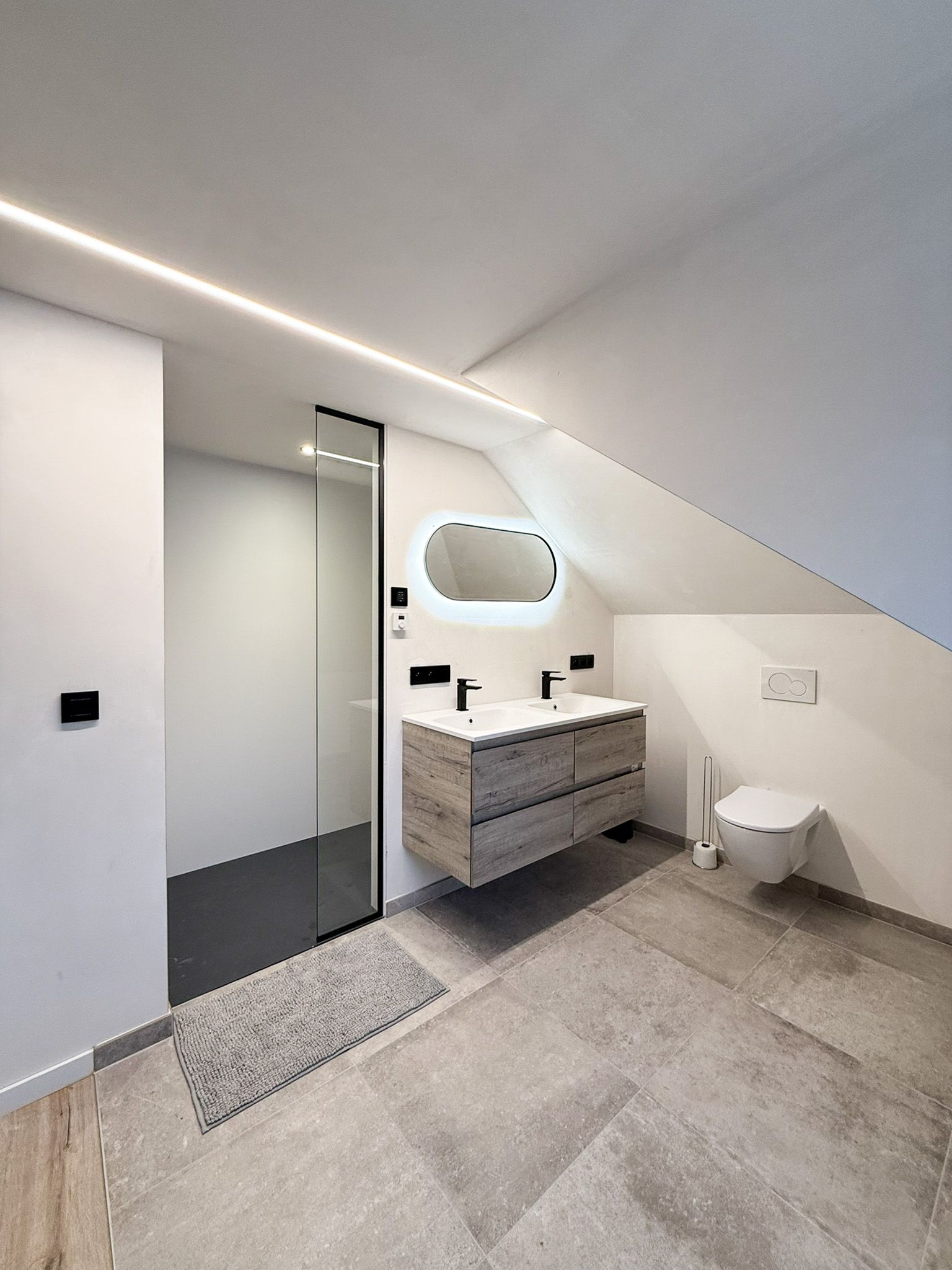 Moderne badkamer met douche, dubbele wastafel en toilet. Grijstinten met houten accenten.
