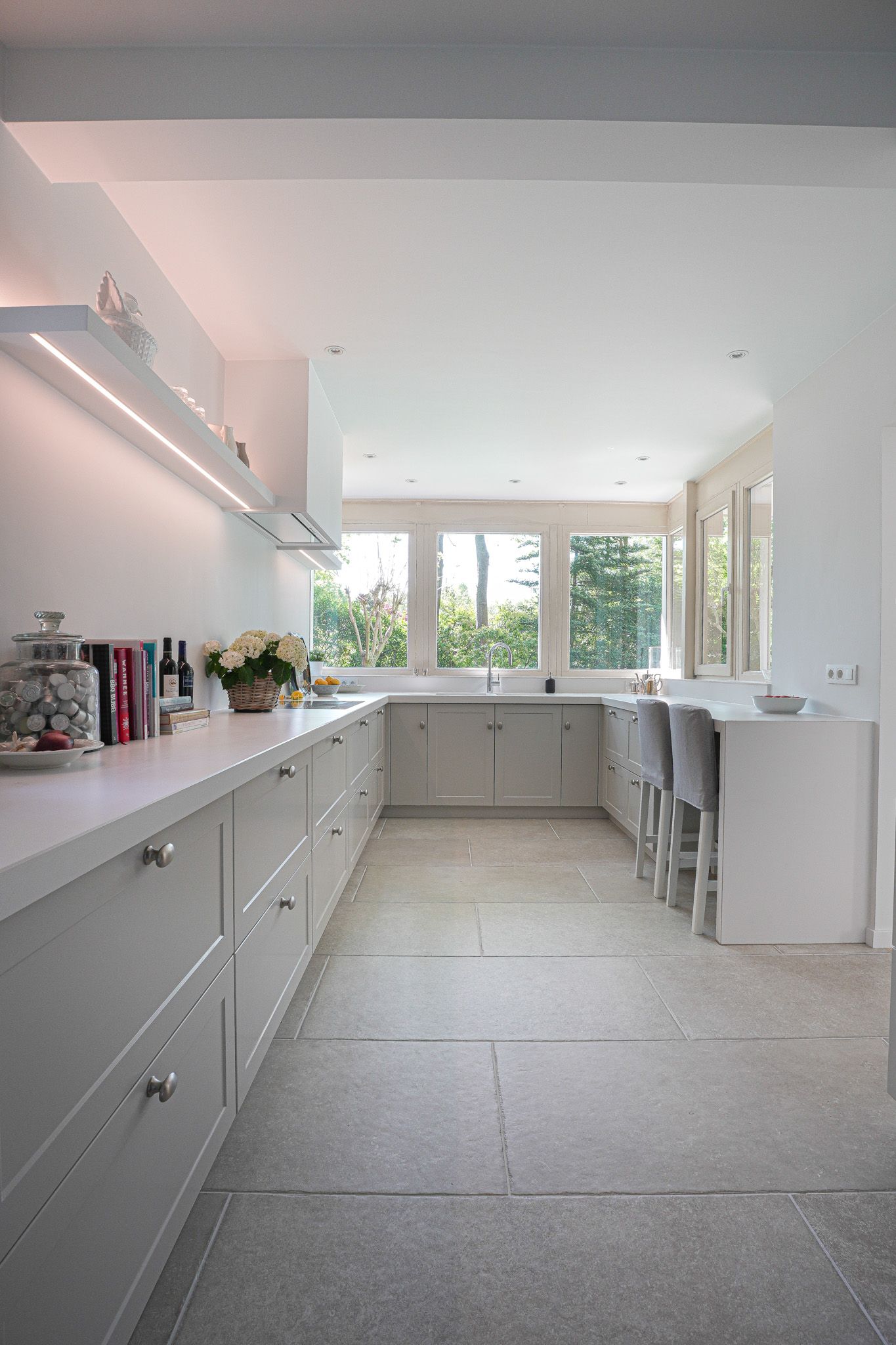 Moderne witte keuken met aanrechtblad, kasten en een ontbijtbar.
