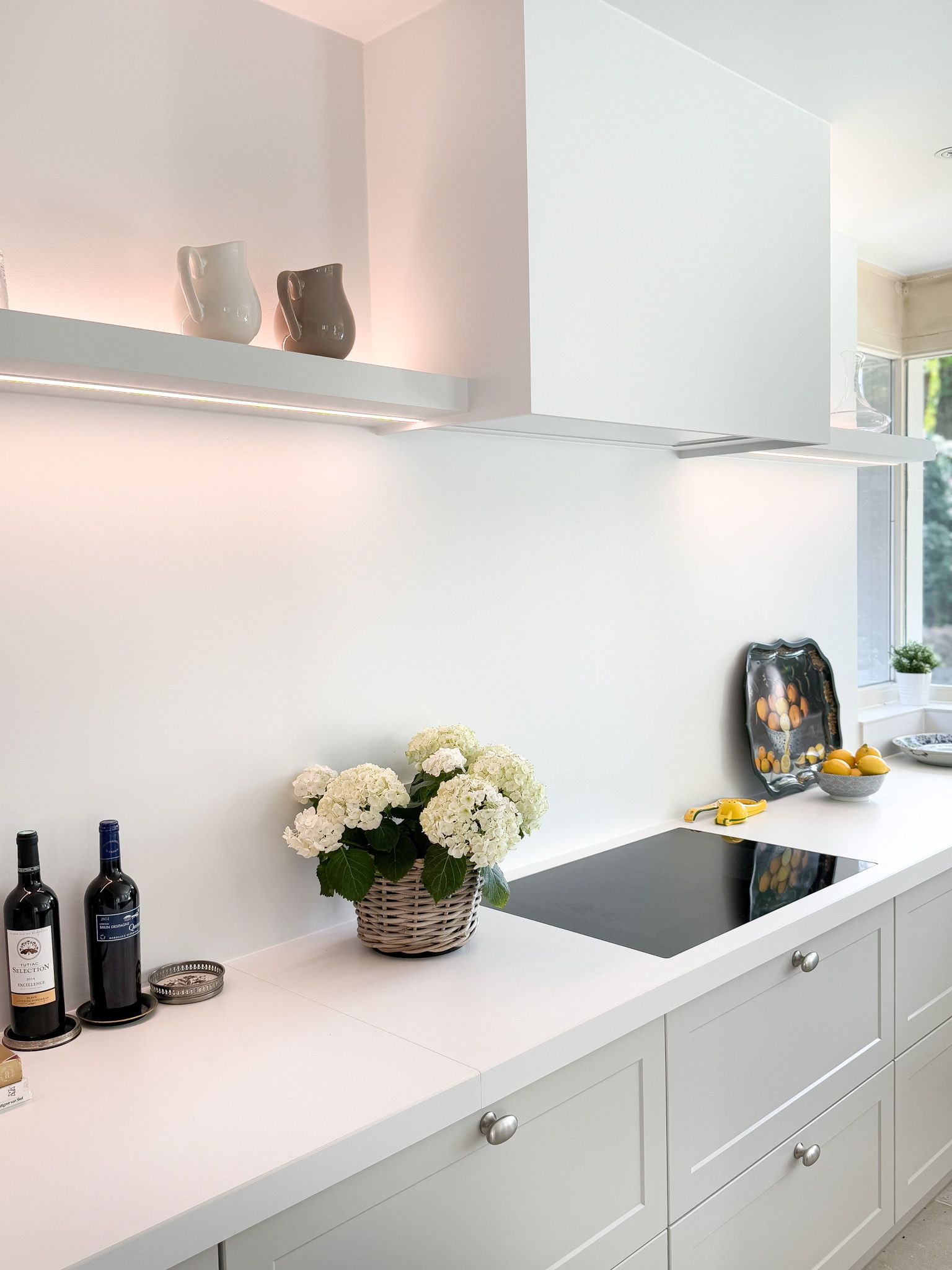 Moderne witte keuken met aanrechtblad, kastjes en een plank met vazen.