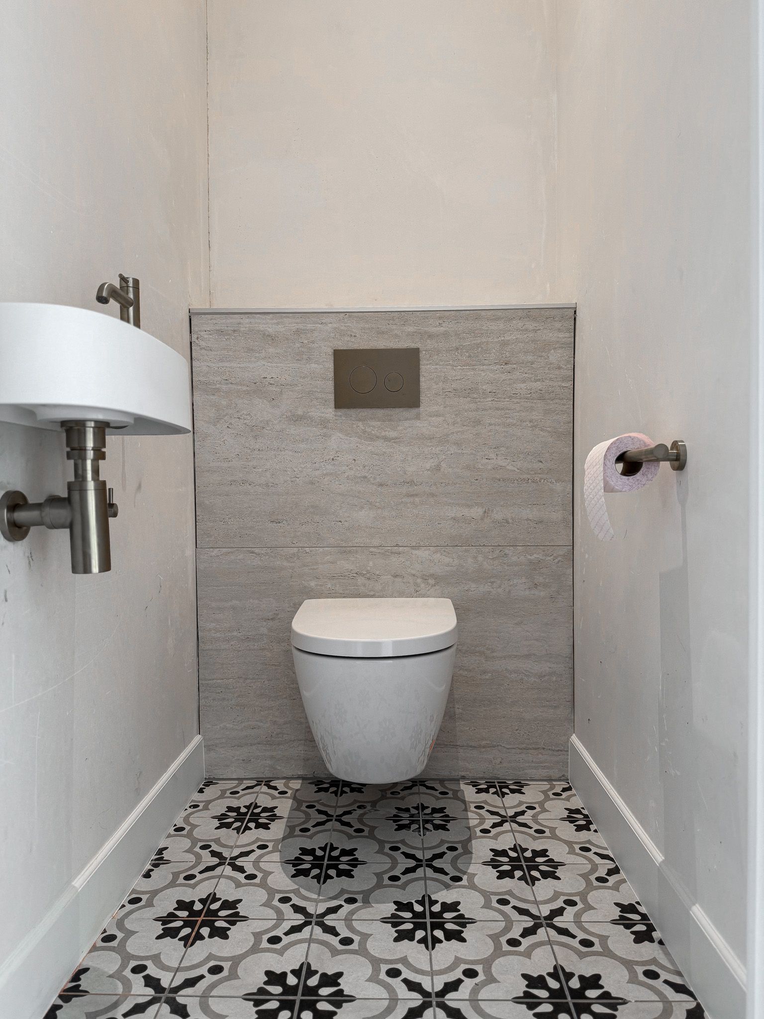 Kleine badkamer met een geblokte vloer, modern toilet, wastafel en een accentmuur in neutrale tinten.