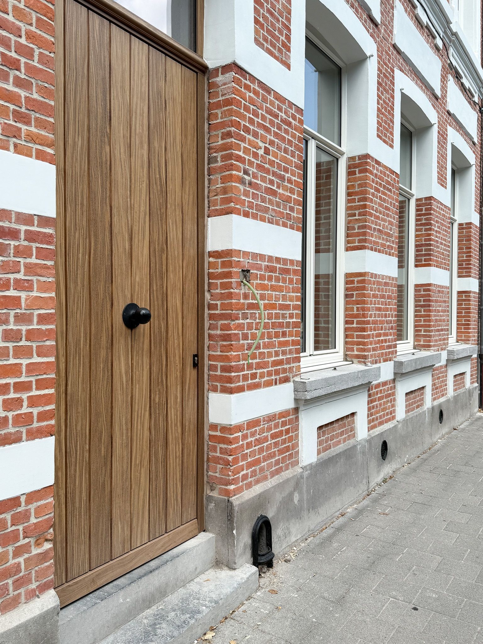 Houten deur en bakstenen gebouw met witte accenten.