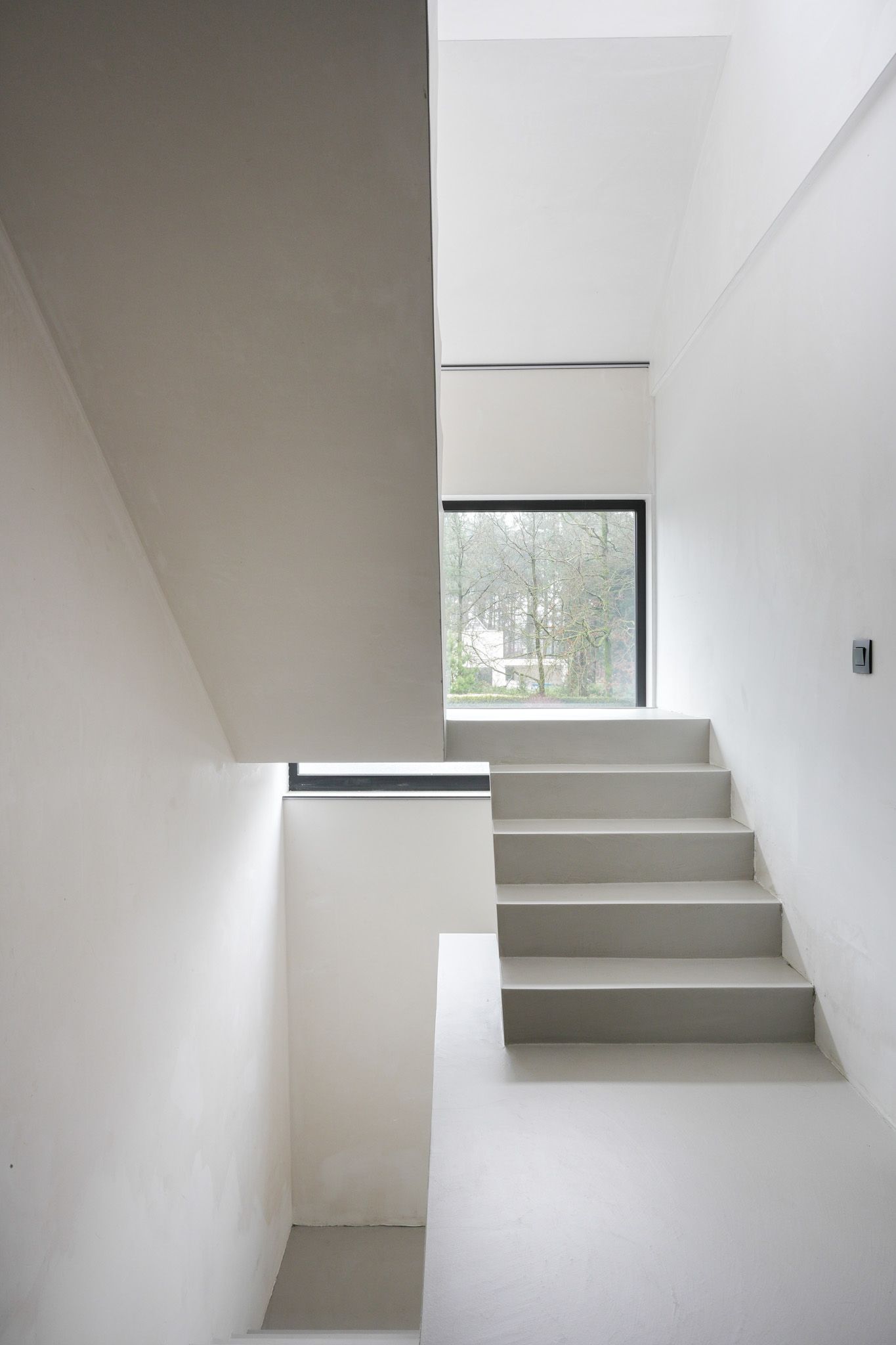 Witte minimalistische trap met een raam dat uitzicht biedt.