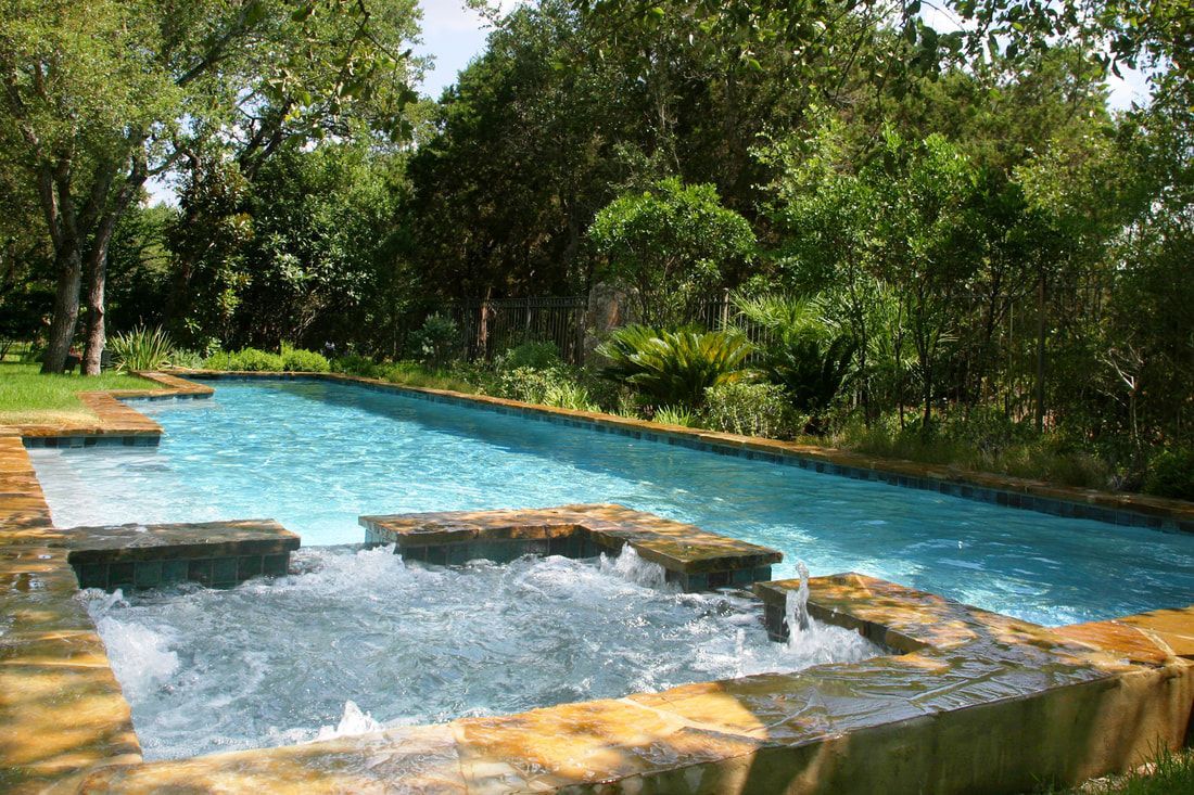 A large swimming pool with a hot tub in the middle of it surrounded by trees.