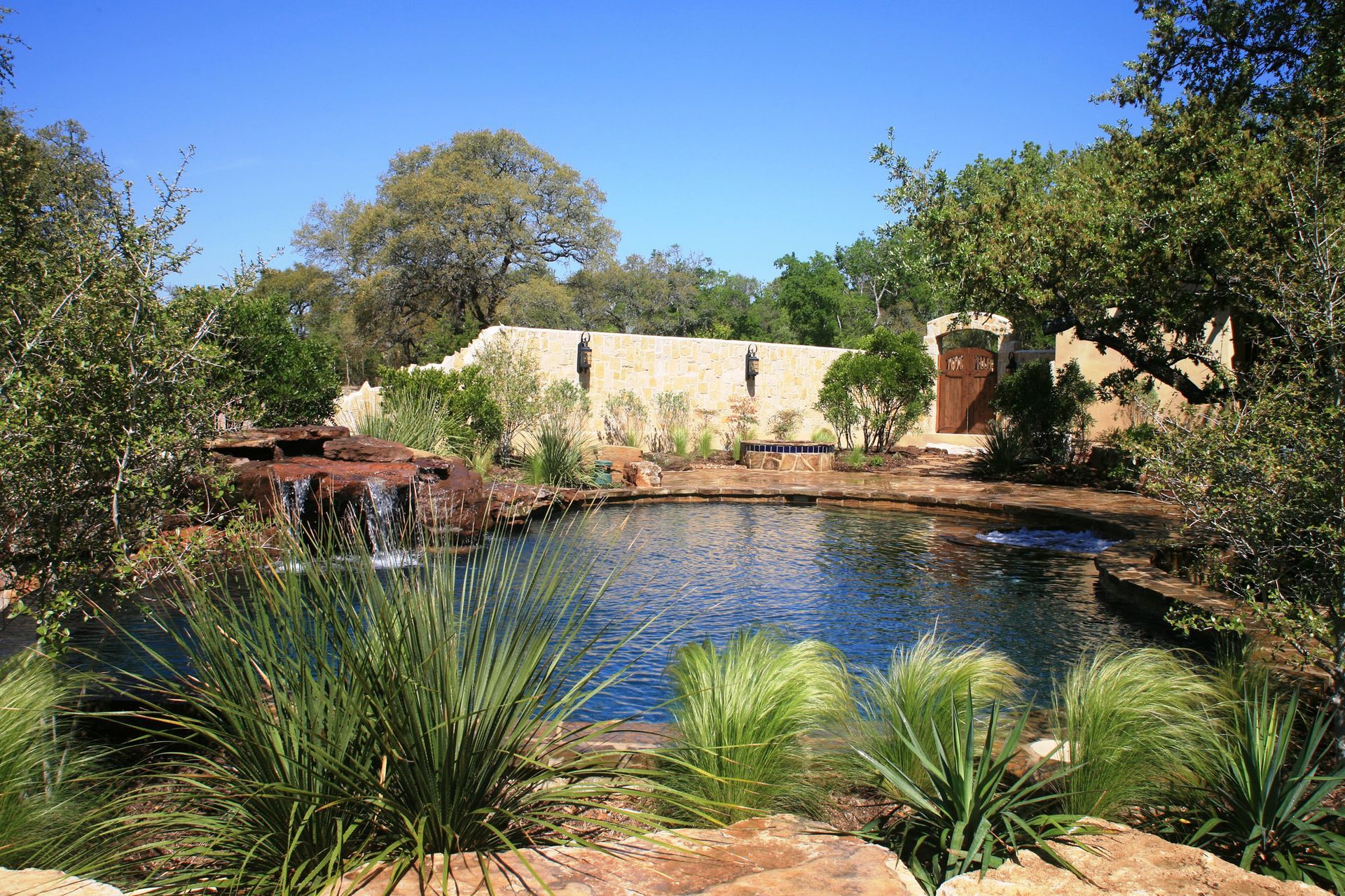 A large pond with a waterfall in the middle of a lush green garden.