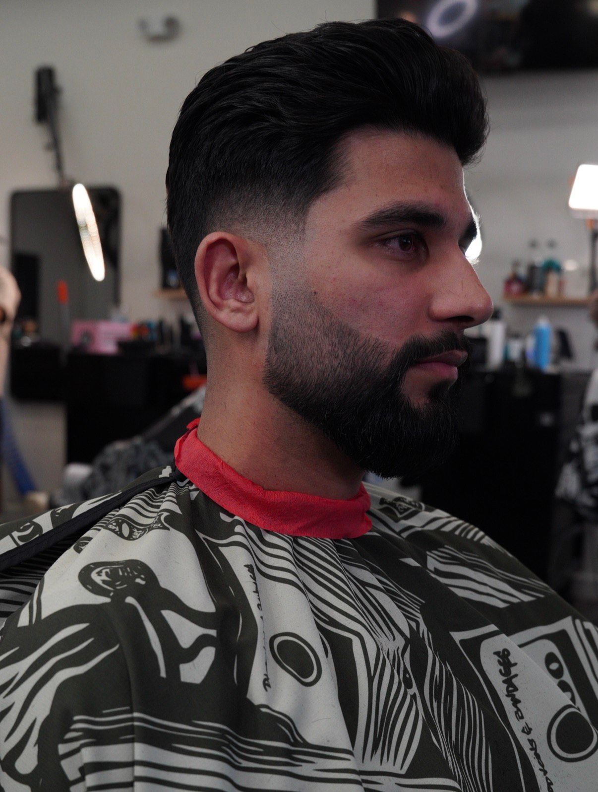 Tattoo artist styling a short-haired client's hair in a salon