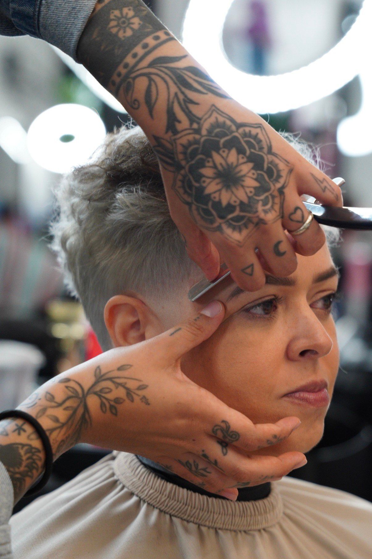 Tattoo artist styling a short-haired client's hair in a salon