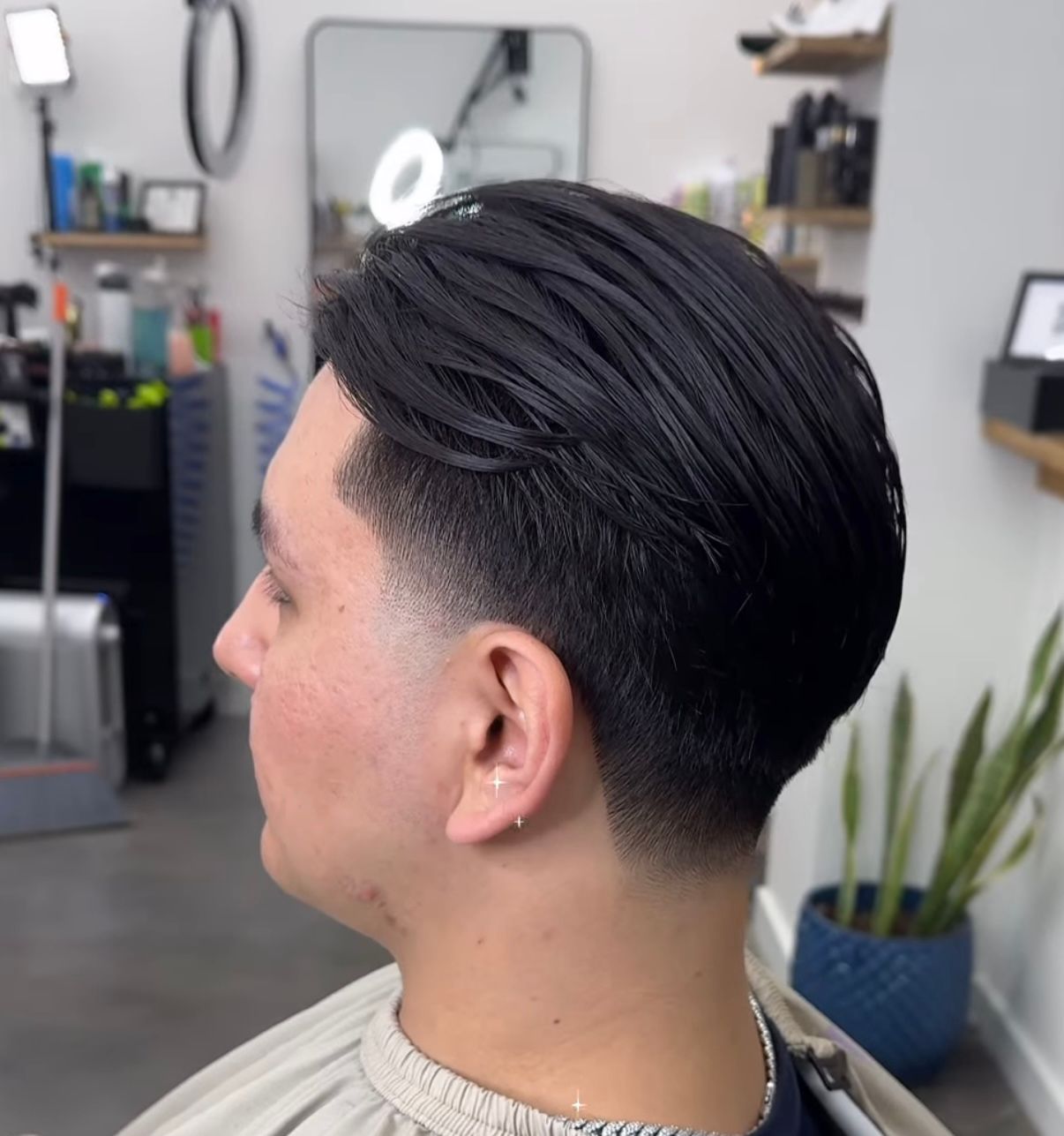 Side view of a neat black undercut hairstyle in a barber shop mirror station.