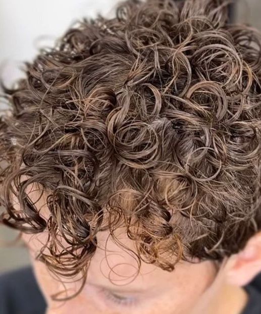 Close-up of curly brown hair with a few loose curls falling over the forehead