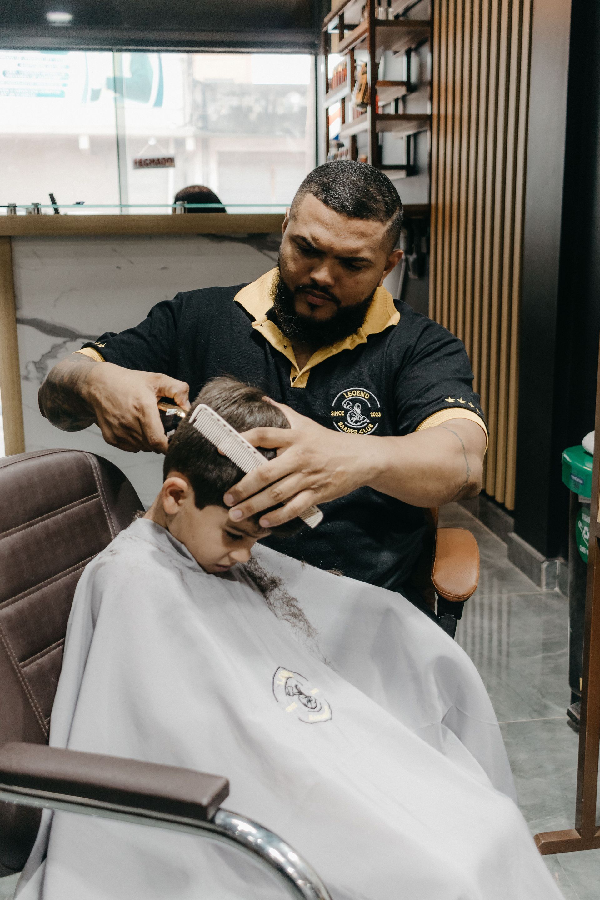 A young kid in a barber chair getting a haircut.