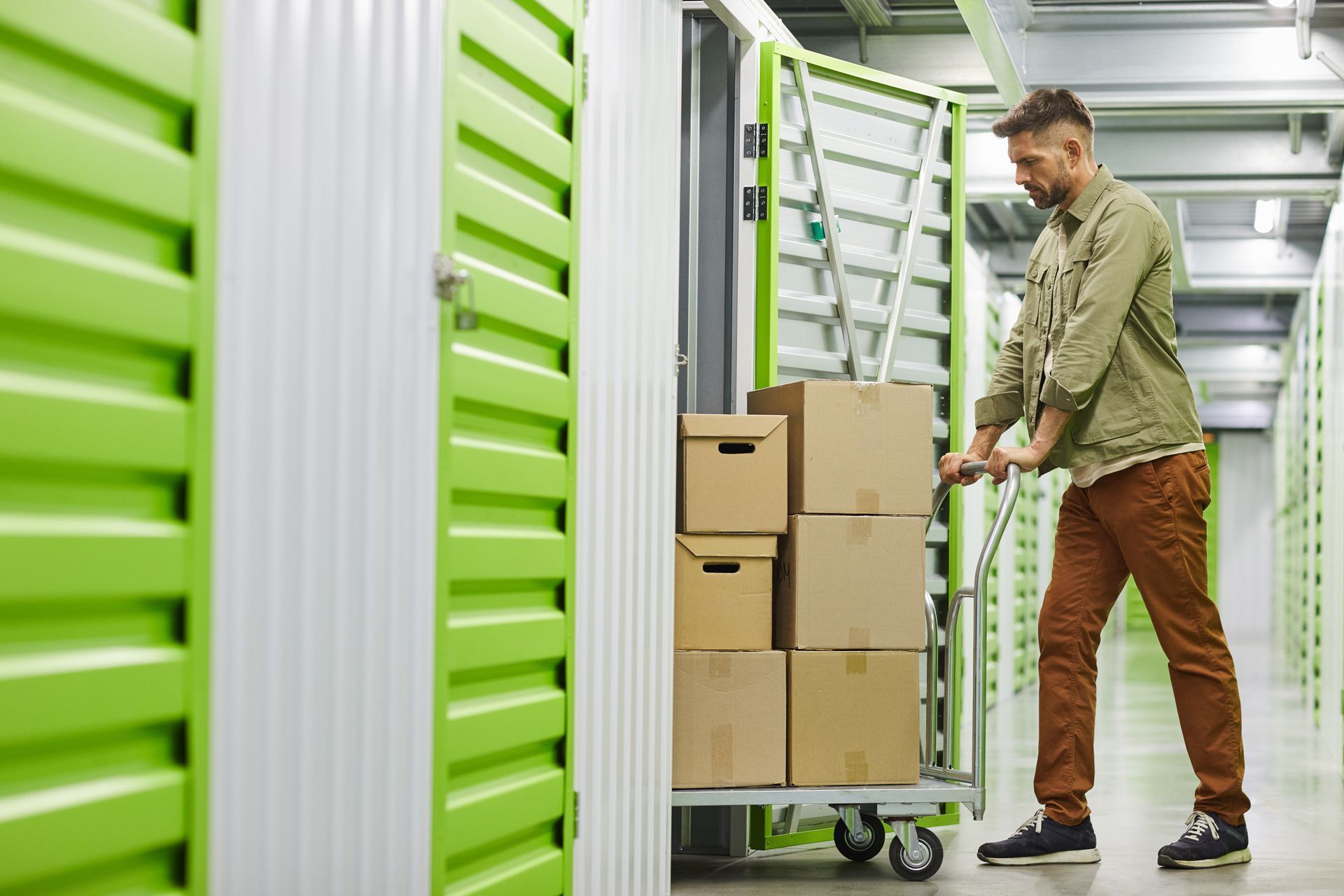A man is pushing a cart with boxes into a storage.