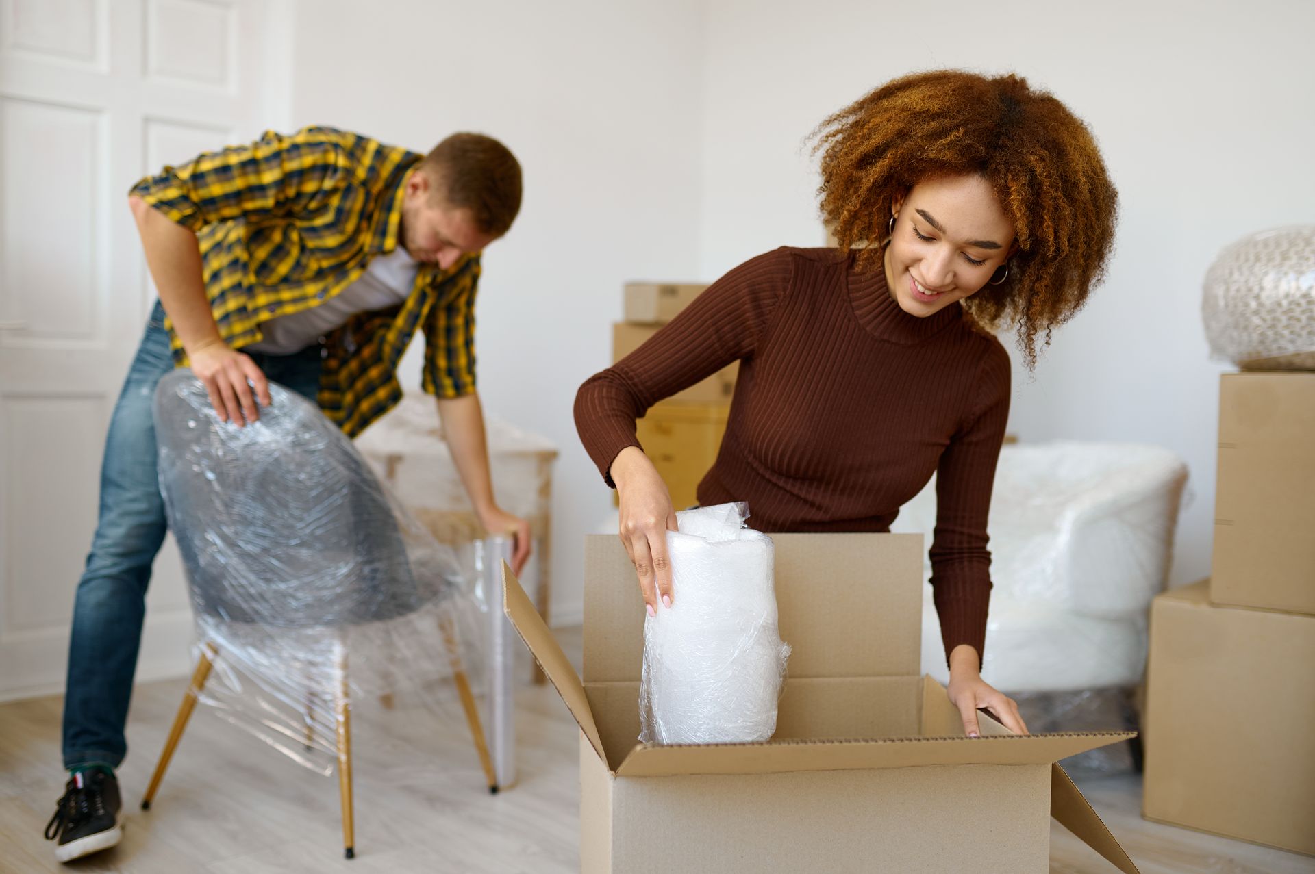 Happy couple wrapping and packing belongings before moving.