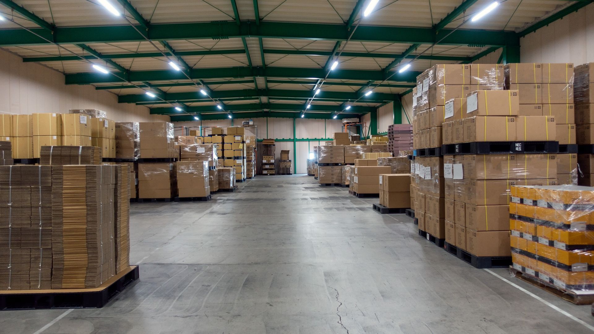 Warehouse storage facility with rows of cardboard boxes stacked on pallets.