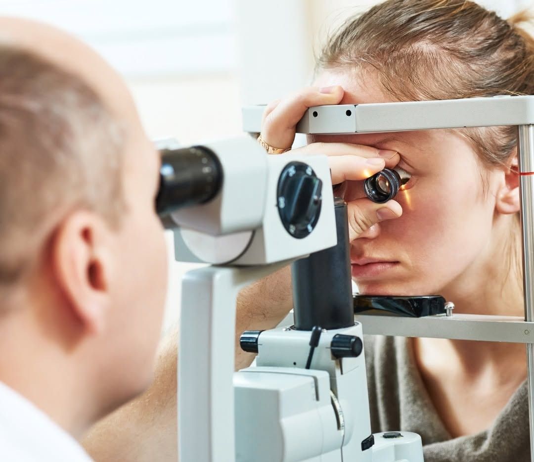 Un optometrista esamina l'occhio di un paziente con una lampada a fessura in una clinica ben illuminata.