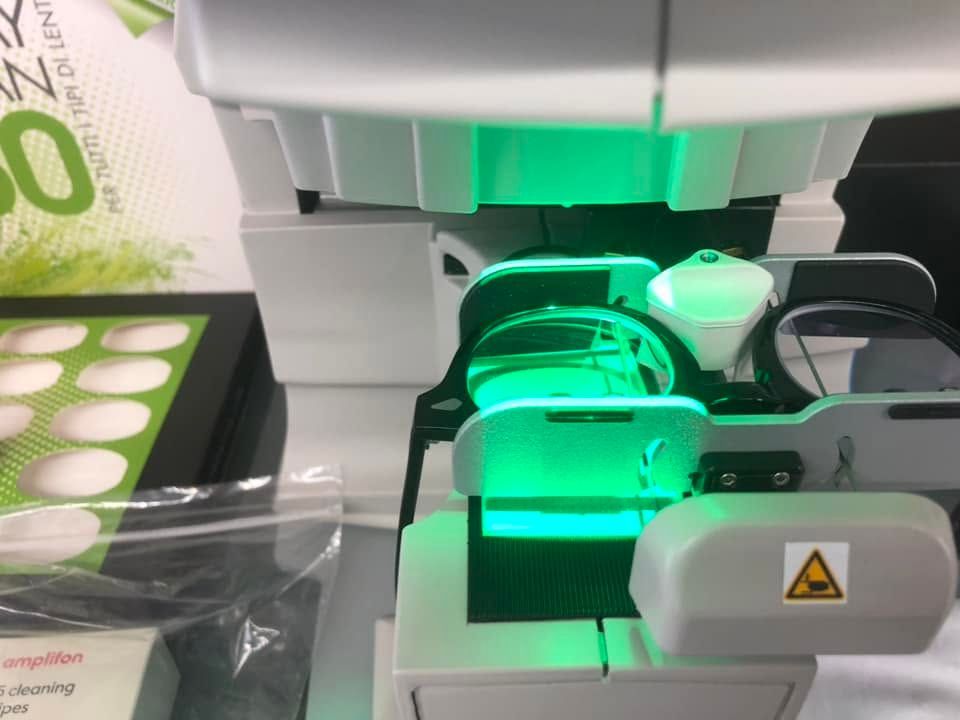 Primo piano di uno strumento da laboratorio illuminato di verde che carica vassoi di campioni in una macchina