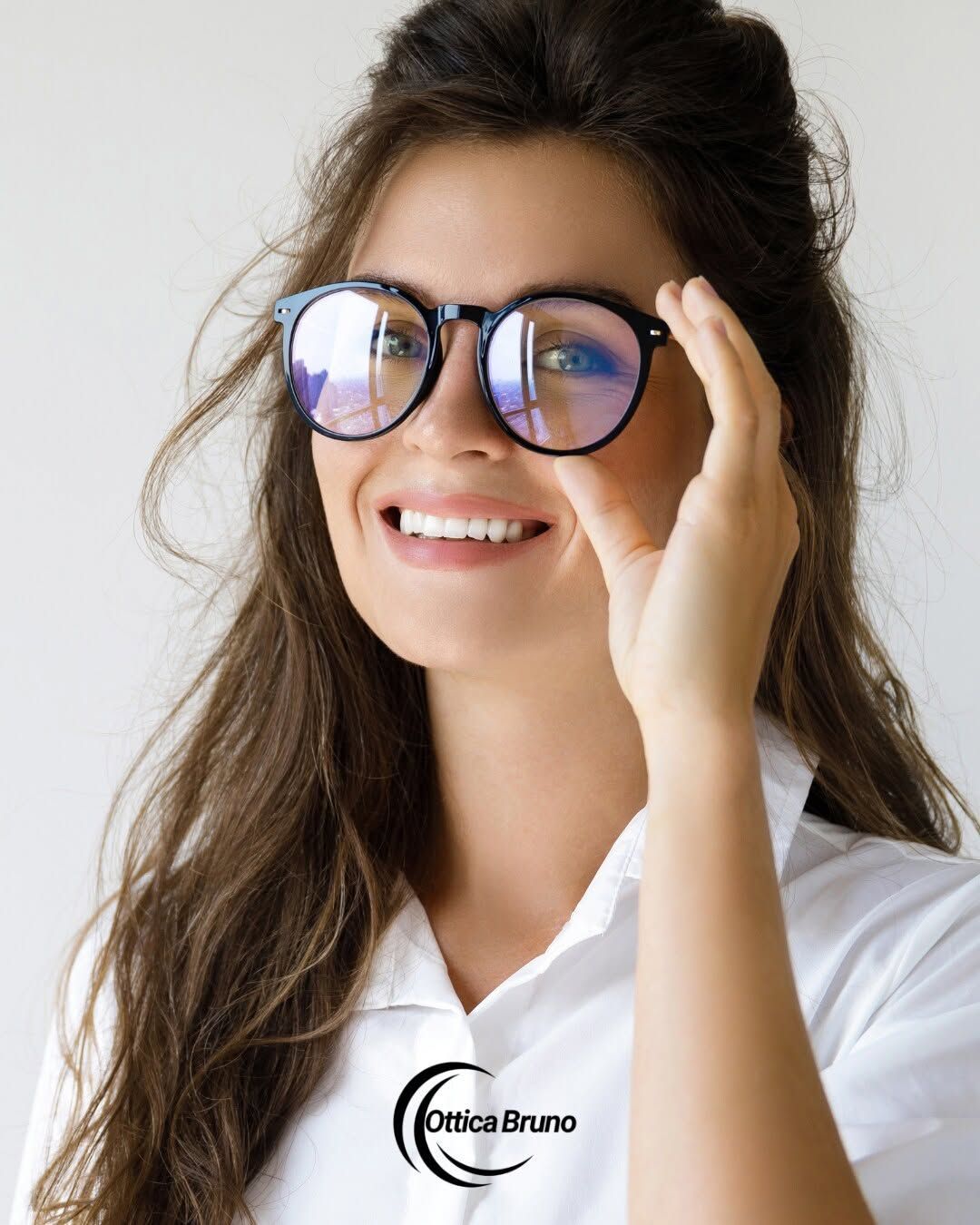 Donna sorridente con occhiali rotondi e camicia bianca su sfondo chiaro