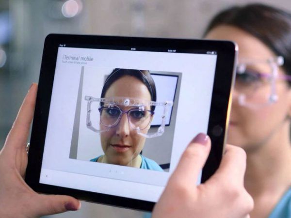 Schermo del tablet che mostra una donna con occhiali protettivi durante una videochiamata con un medico.