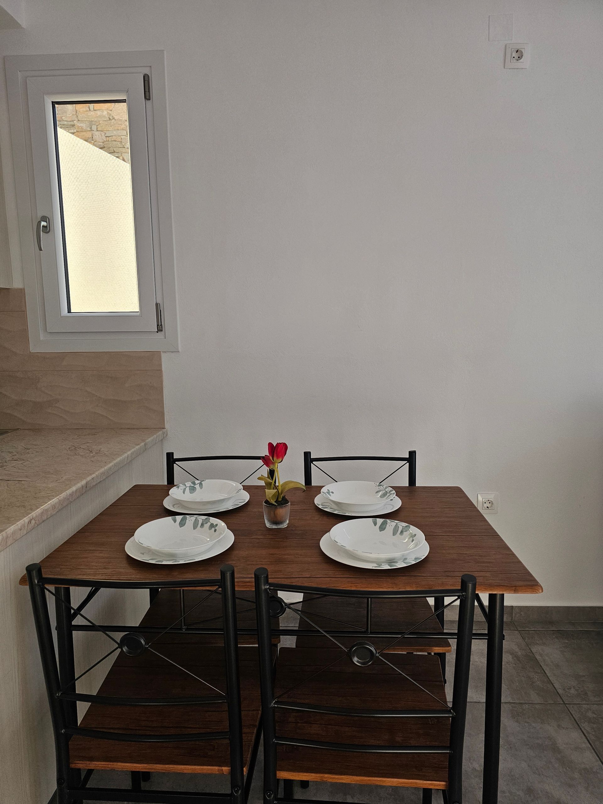 Small dining table set with two place settings beside a kitchen counter and mirror.