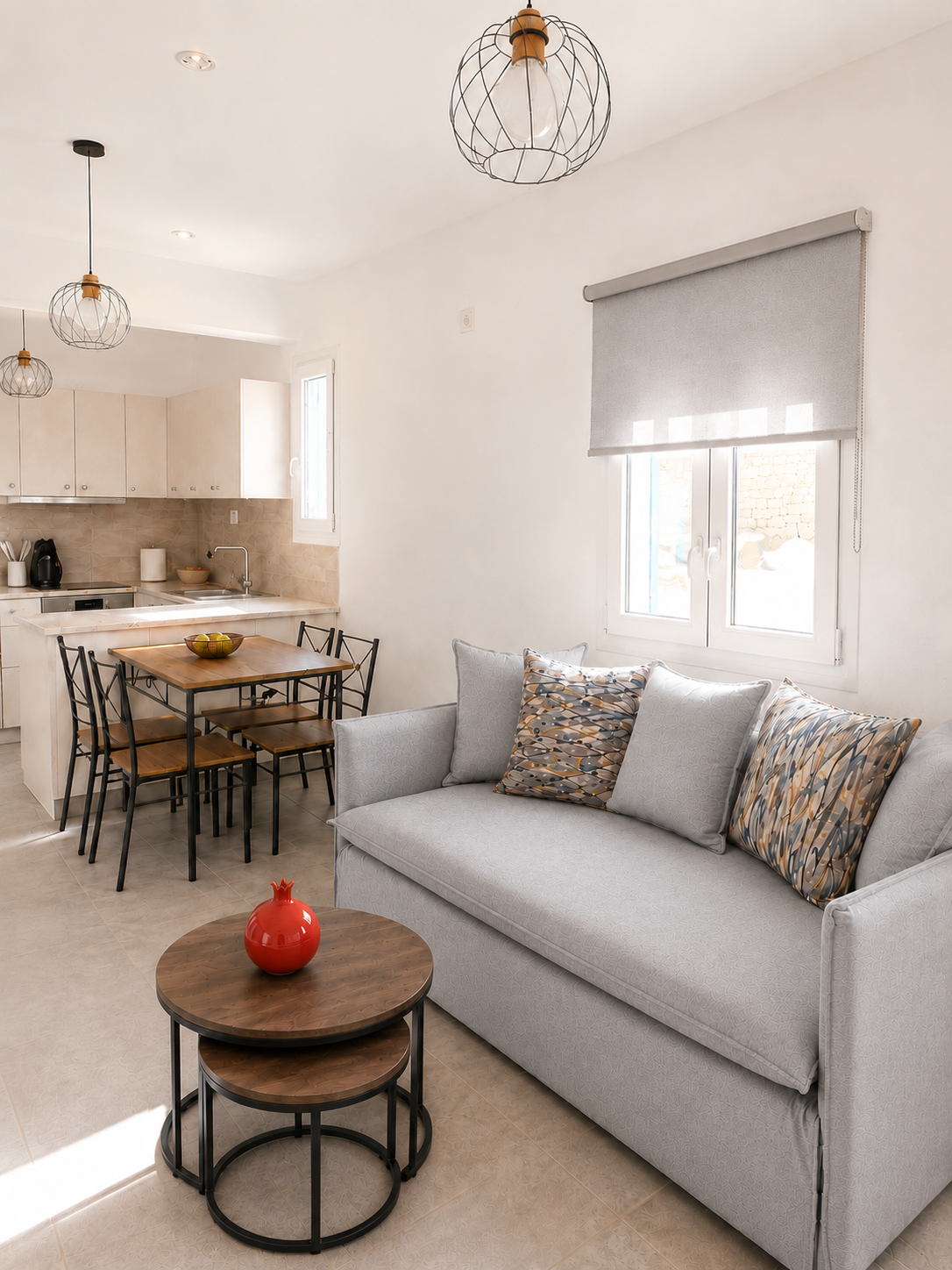 Bright modern living room with a gray sofa, round coffee table, and open kitchen in the background