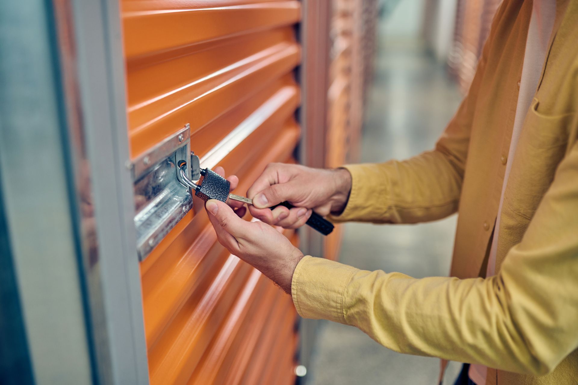 A man is opening the lock of a storage unit.