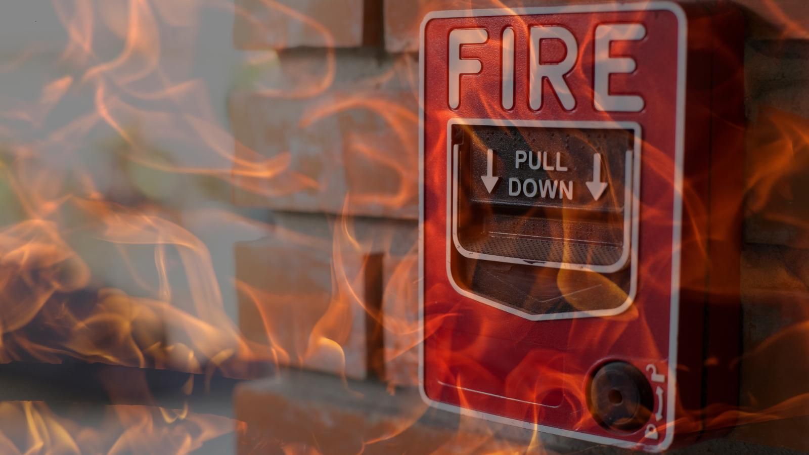 Red fire alarm pull station with flames and smoke in the background