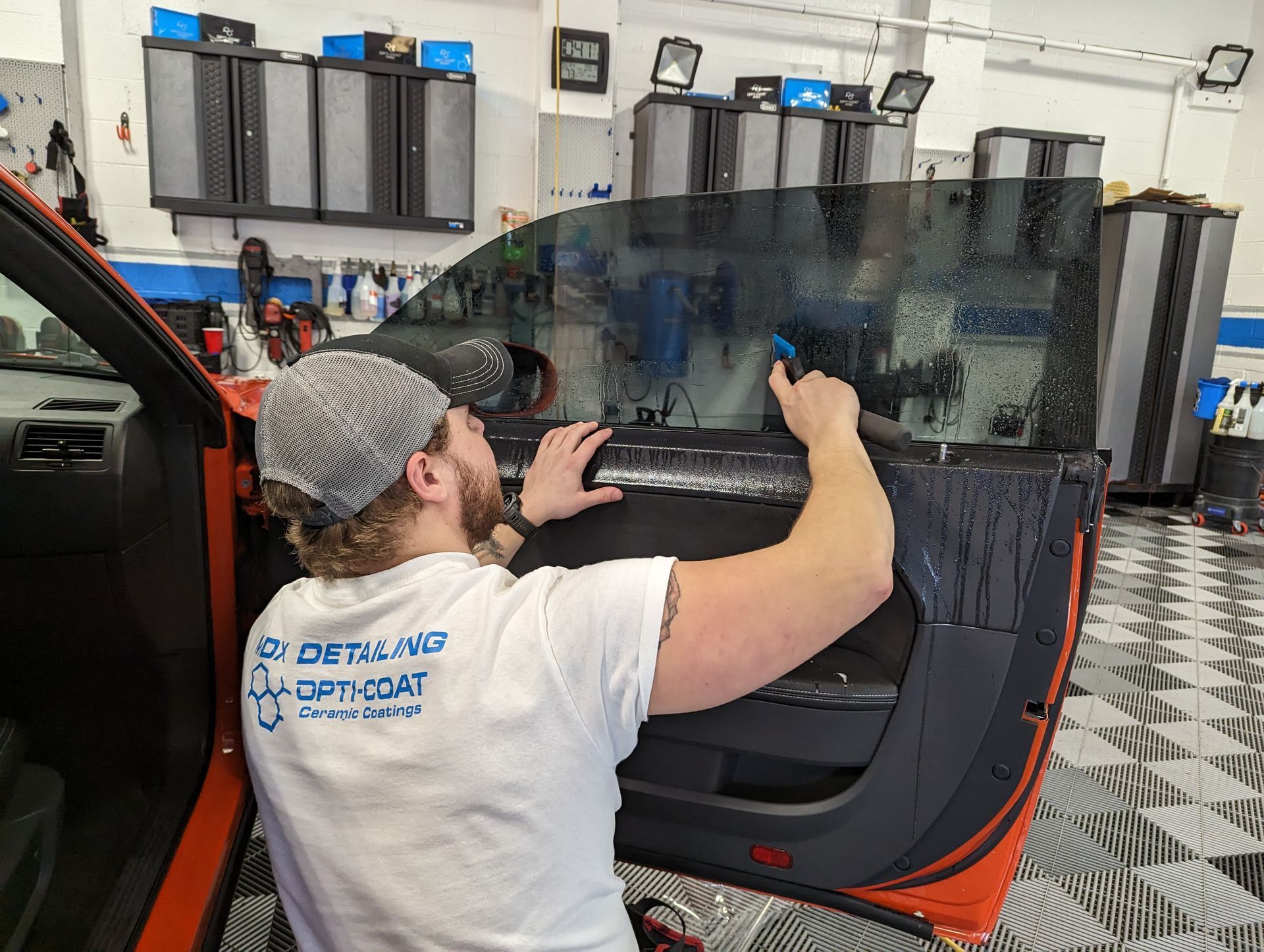 a man is applying window tinting to a car door . Ceramic coating, PPF, Tint, Vinyl Wrap, johnstown www.mdxdetailing.com
