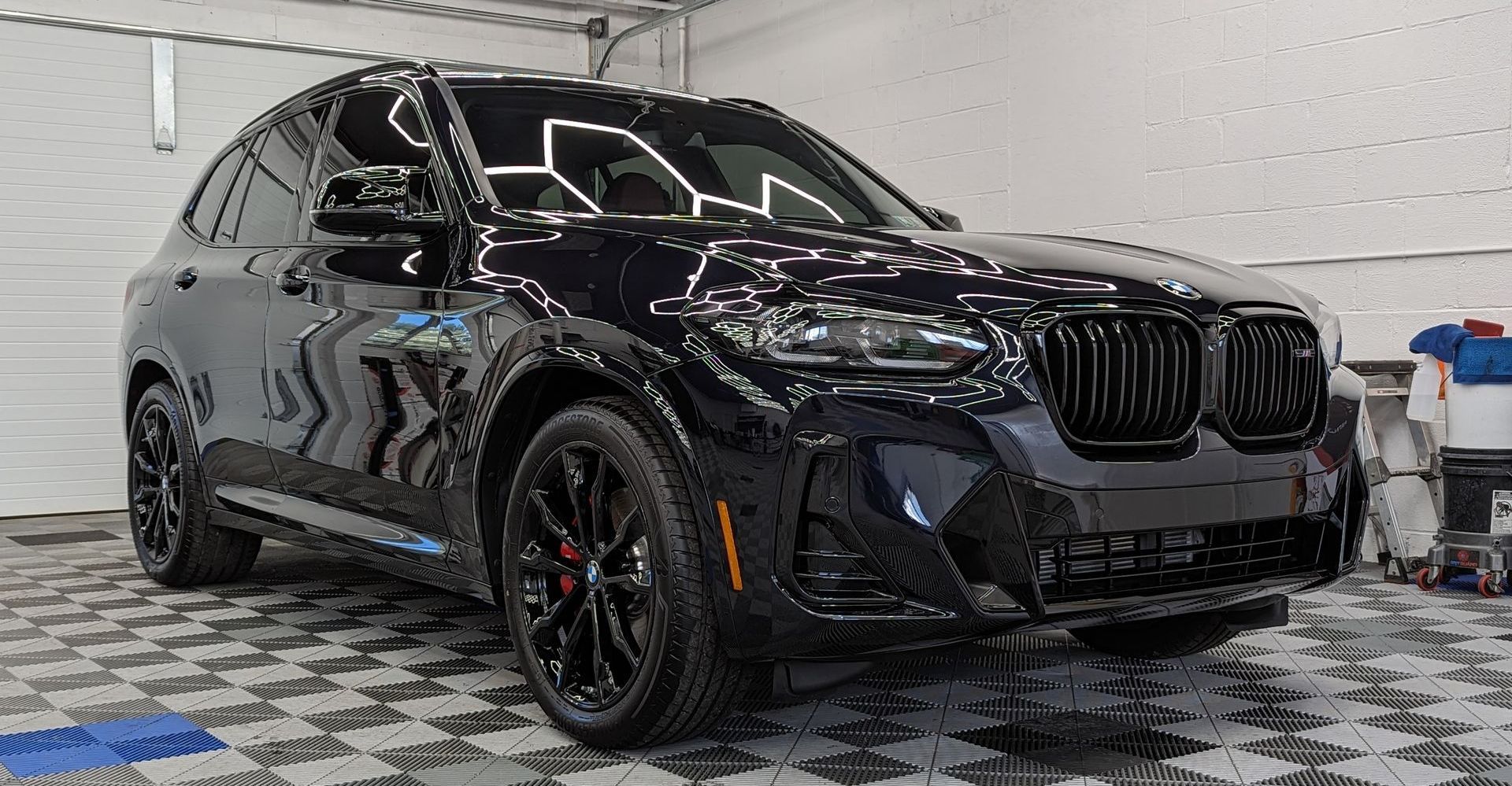 a black bmw x3 is parked in a garage . ceramic coating. ppf window tint. johnstown pa