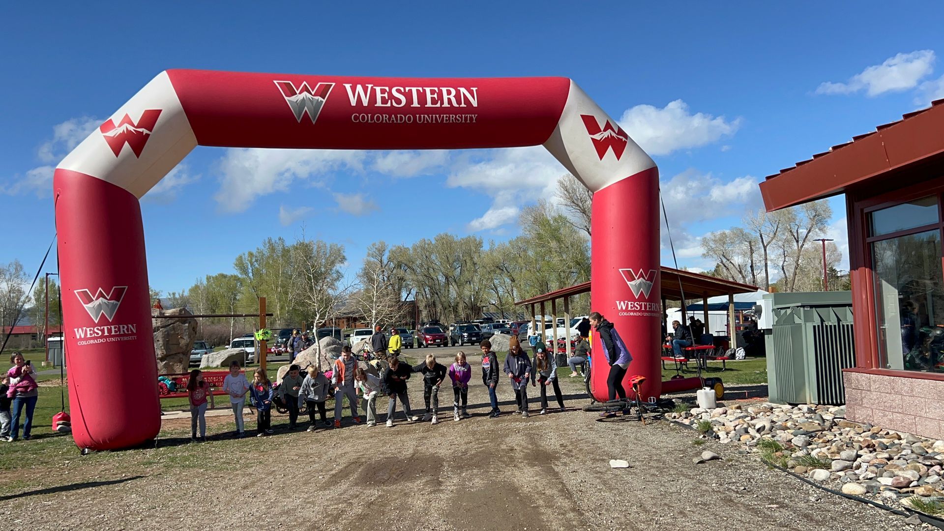 Group of people standing at a race starting line under a red and white archway.