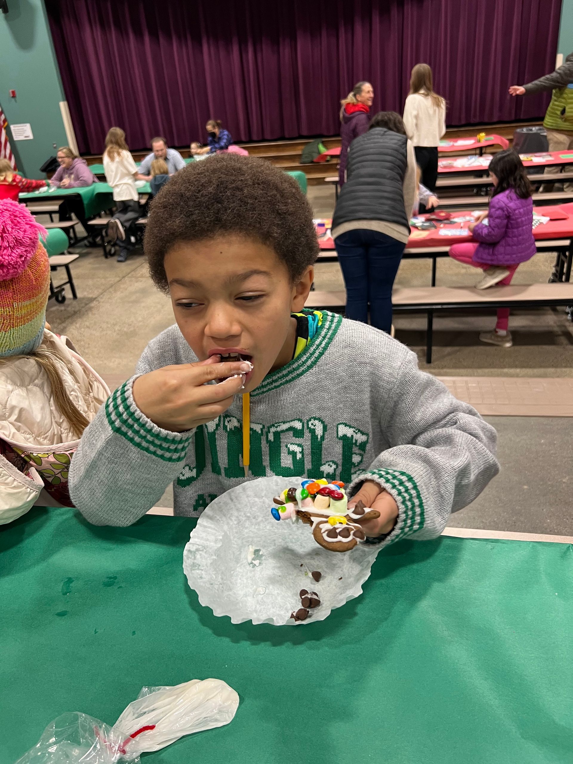 Boy eating a decorated cookie at a table in a school cafeteria.