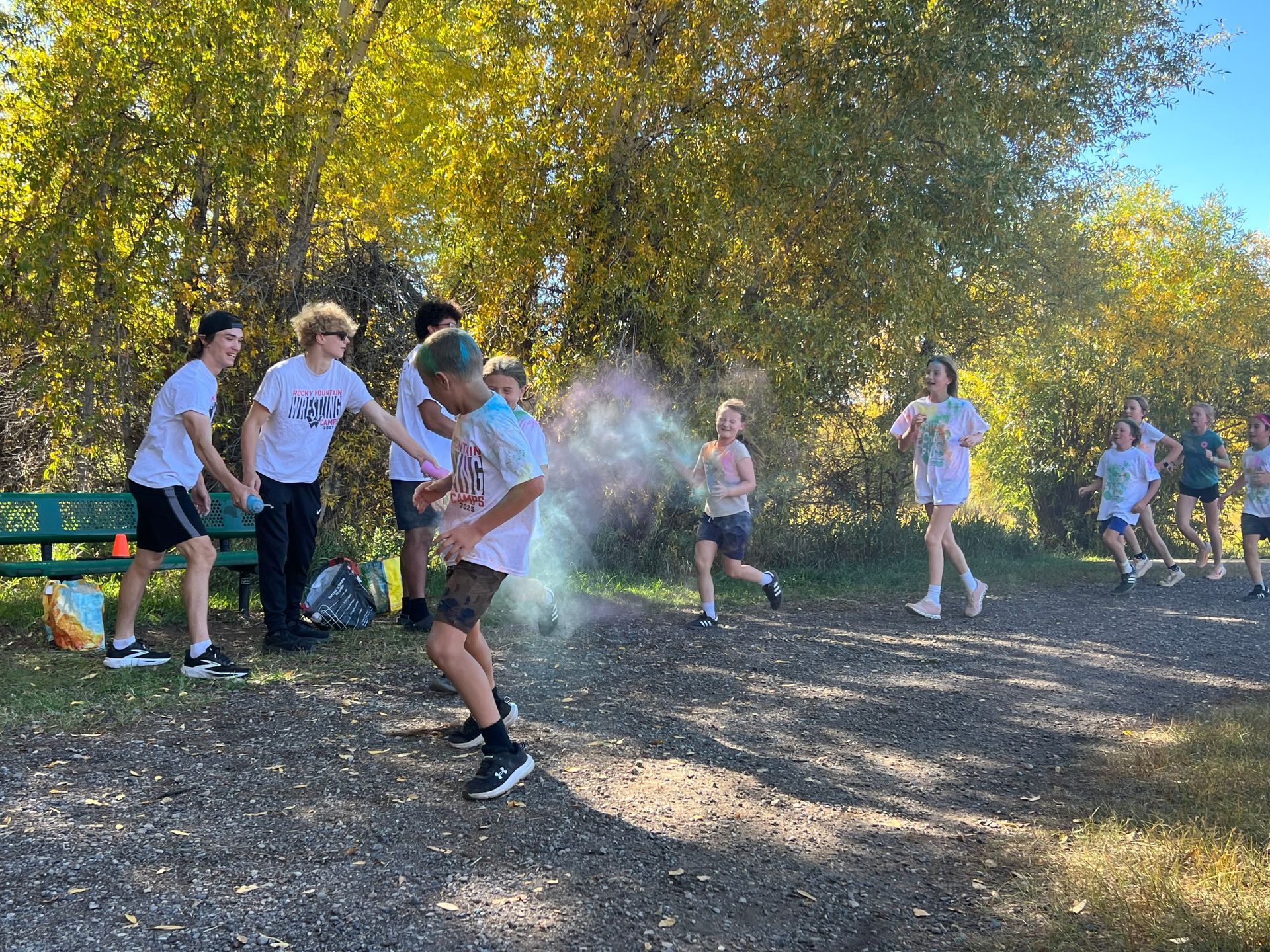 Group of people participating in a color run outdoors, being showered with colorful powder.