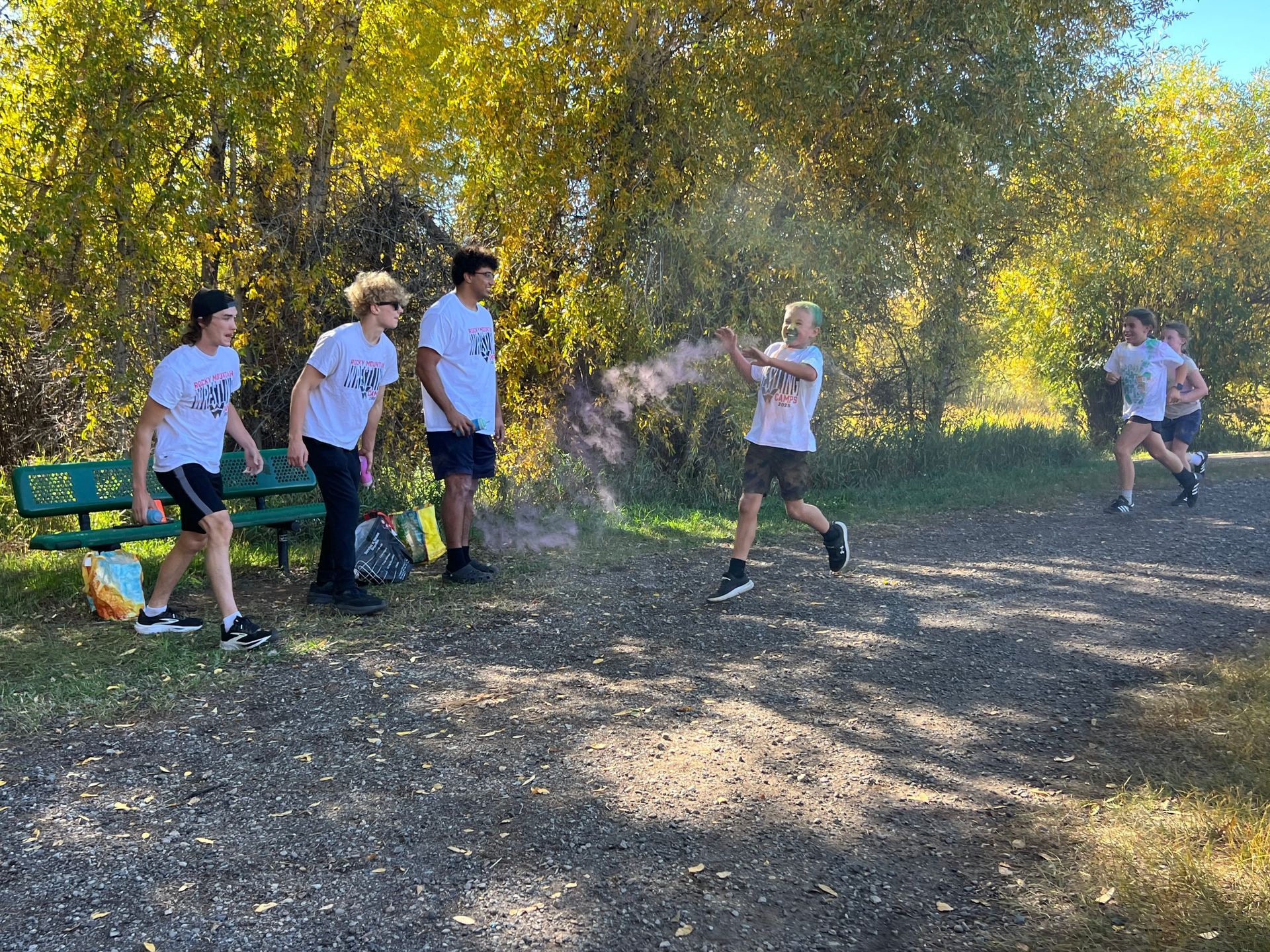 Group of teens playing outdoors; one throws a cloud of powder, others watch.