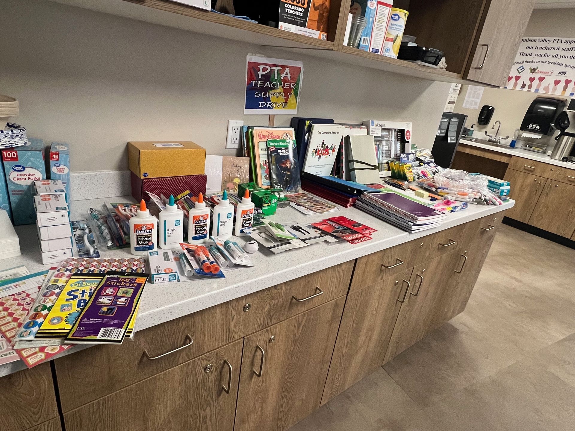 Countertop with school supplies: glue, books, pens, and paper, arranged neatly.