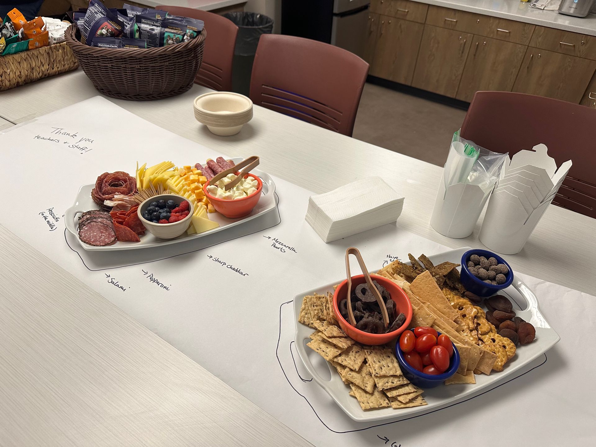A table with charcuterie boards, snacks, drinks, and a basket of items.