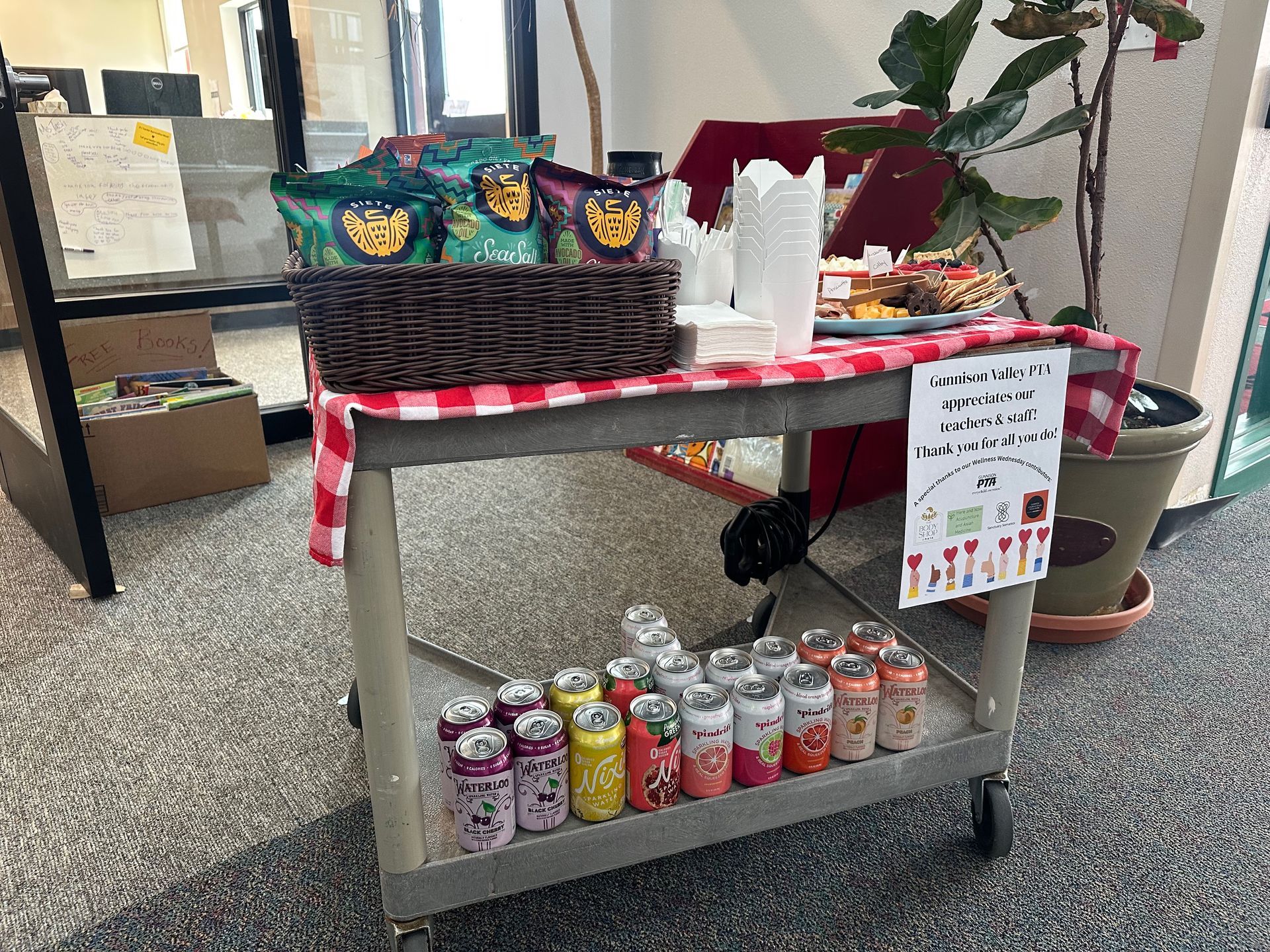A refreshment cart with snacks and drinks. A red and white checkered cloth covers the cart.