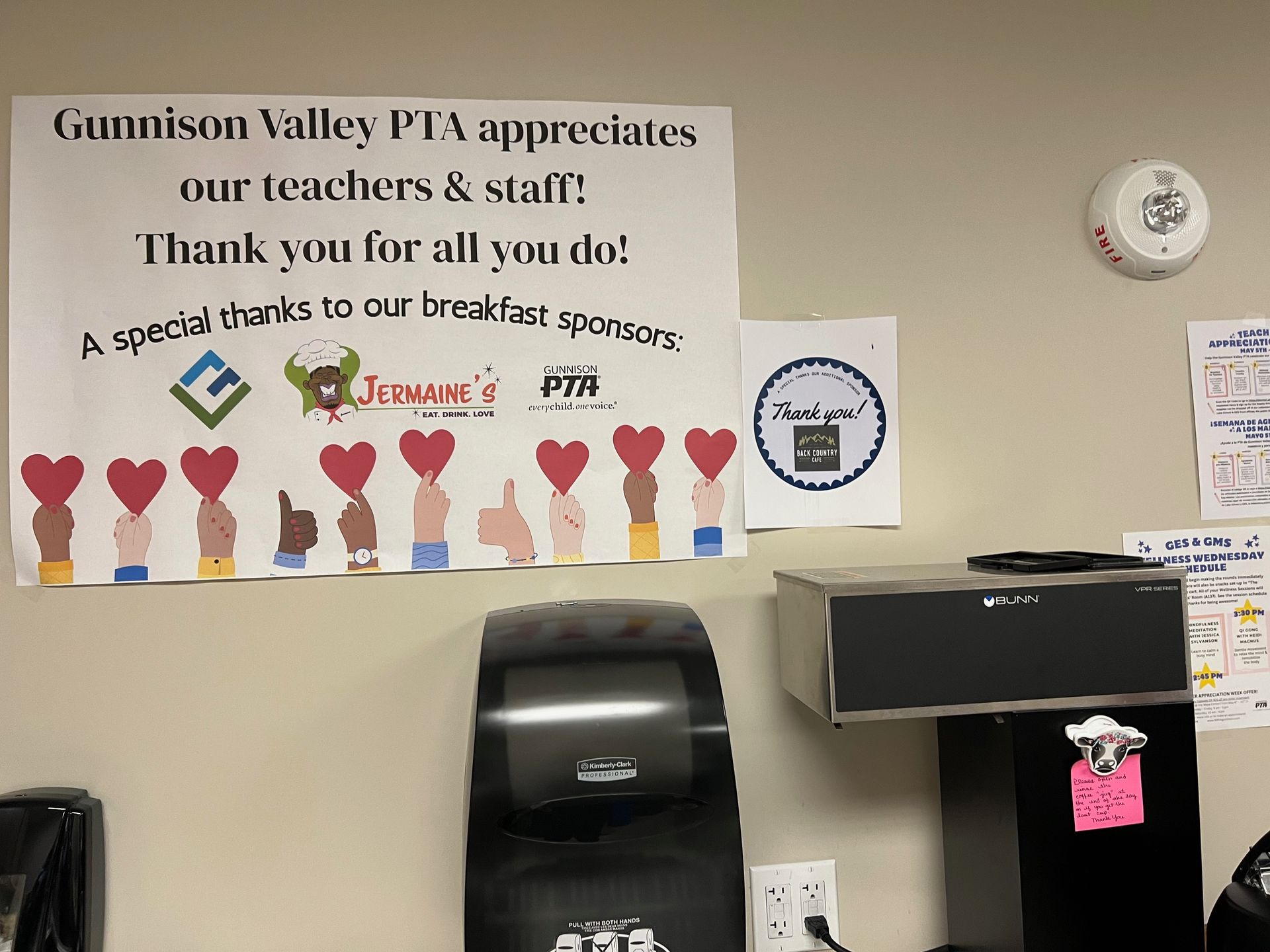 Sign thanking teachers and staff, posted on a wall with a fire alarm and coffee machine.