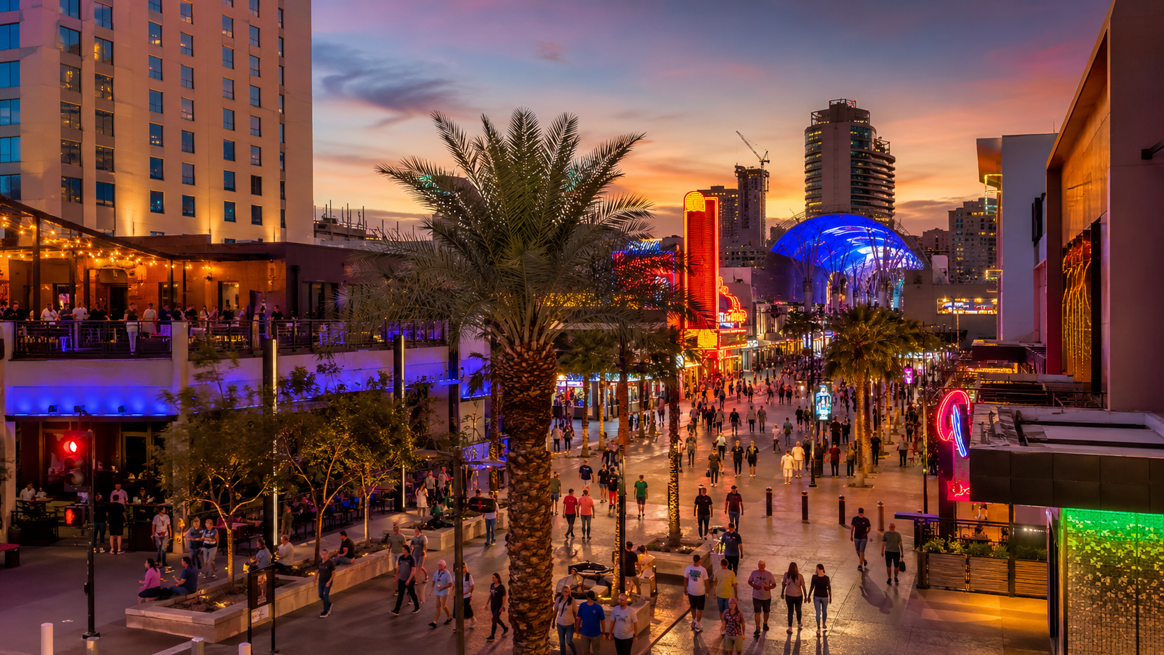 Downtown Las Vegas at dusk with lights, palm trees, storefronts, and visitors exploring the city