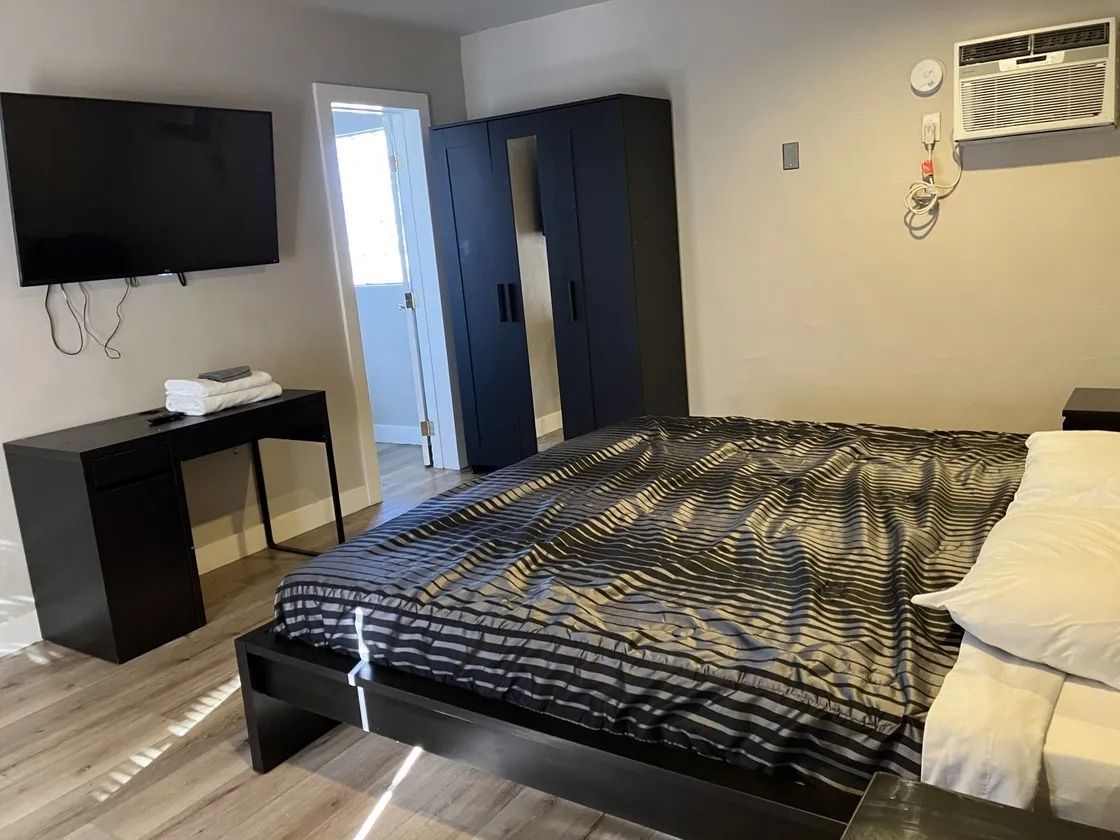 Modern downtown Las Vegas motel room with king bed, wardrobe, TV, and updated guest amenities.