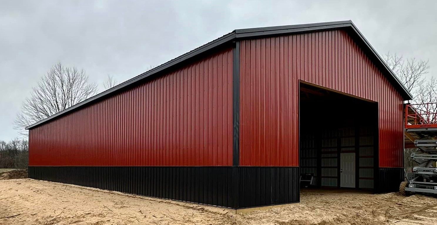 Red and black metal barn with open entrance on overcast day.
