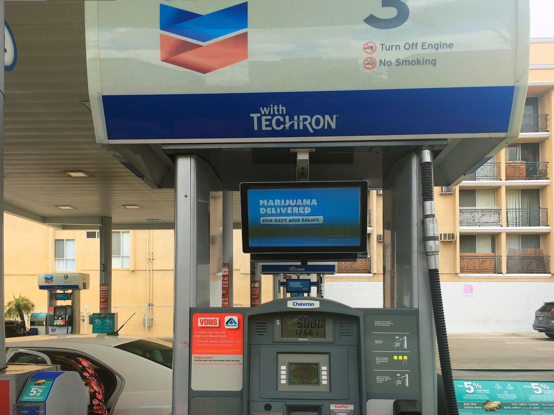 Gas station pump with a blue TecHron sign and digital payment screen under a canopy