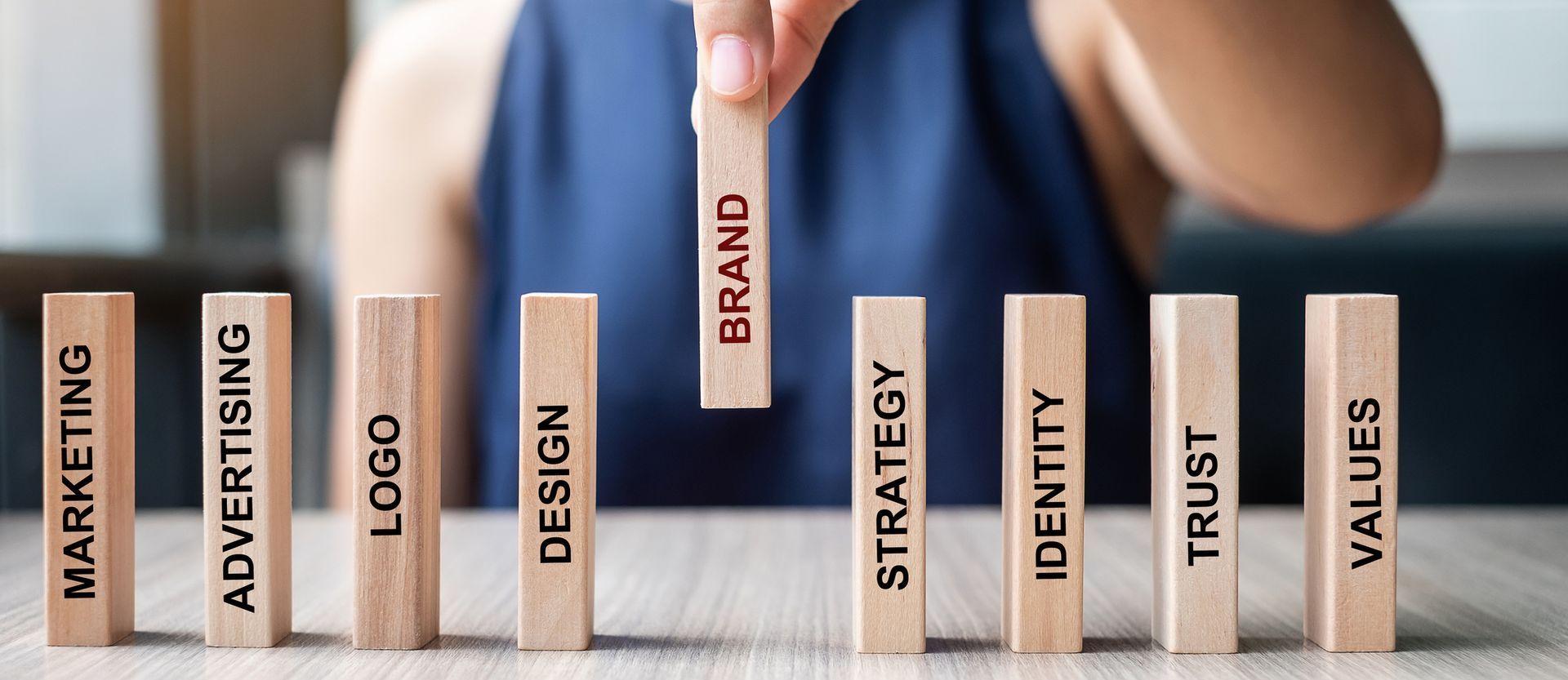 A person is holding a wooden block with the word brand on it