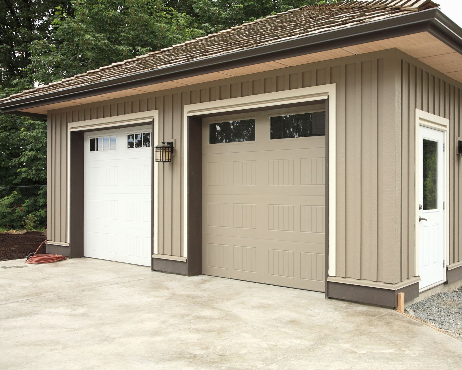 Two-car garage with white and beige doors. Beige siding and brown trim. Concrete driveway.