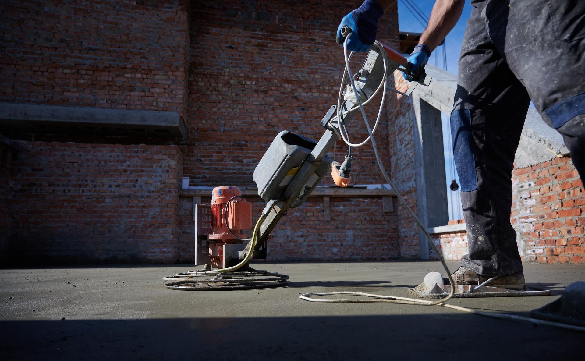 A man is using a machine to finish a concrete floor.