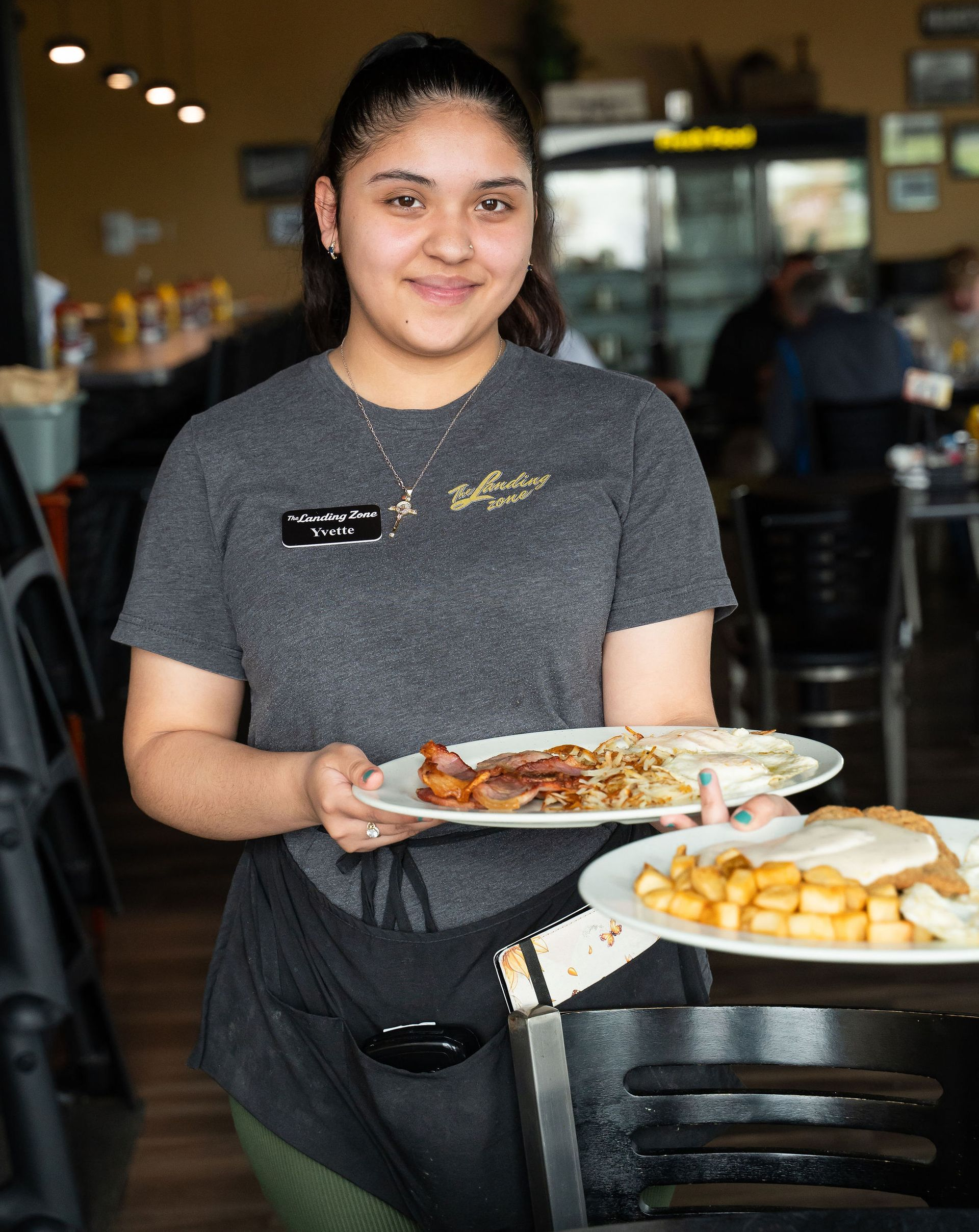 Restaurant server carrying two plates of food in a dining area.