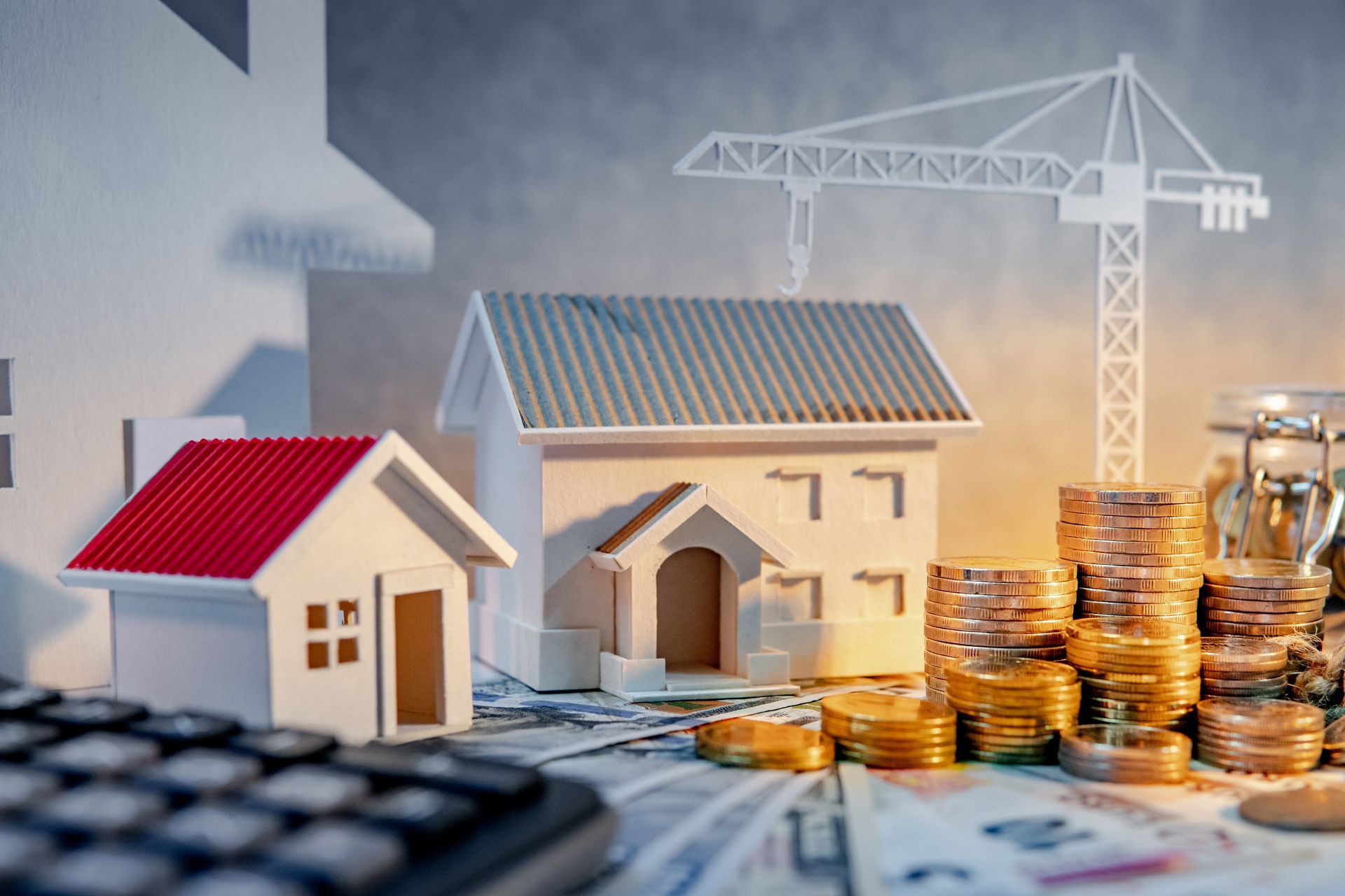 Small house models, stacked coins, and a crane suggest real estate investment or construction savings