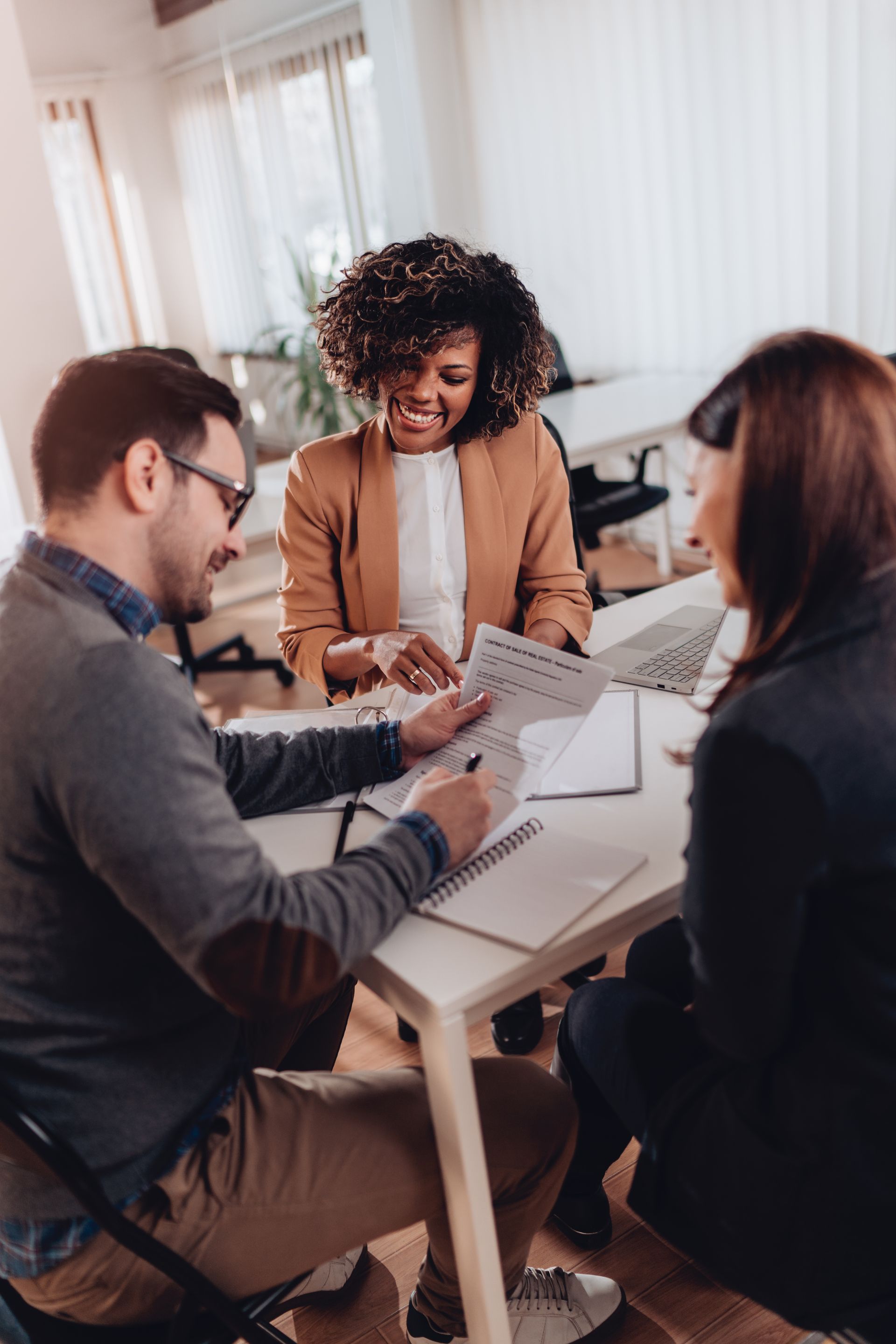 Three coworkers reviewing documents around a table in a bright office