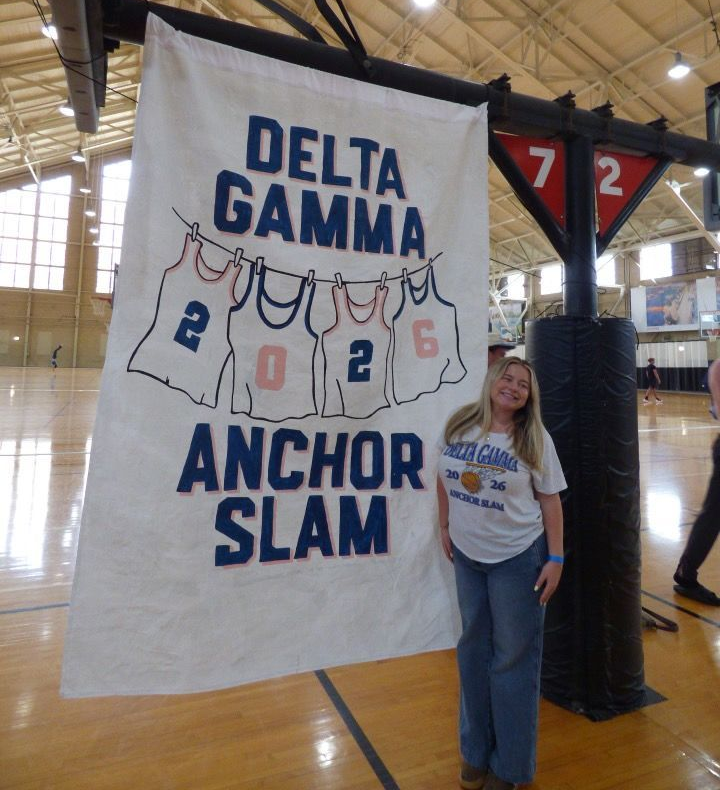 Delta Gamma Anchor Slam Banner with blonde woman standing in front of it smiling