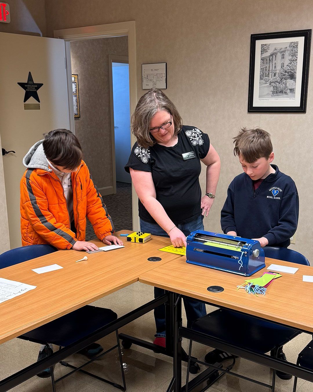 Students from Sacred Heart Middle School work with Ms. Staci to make braille card inserts.